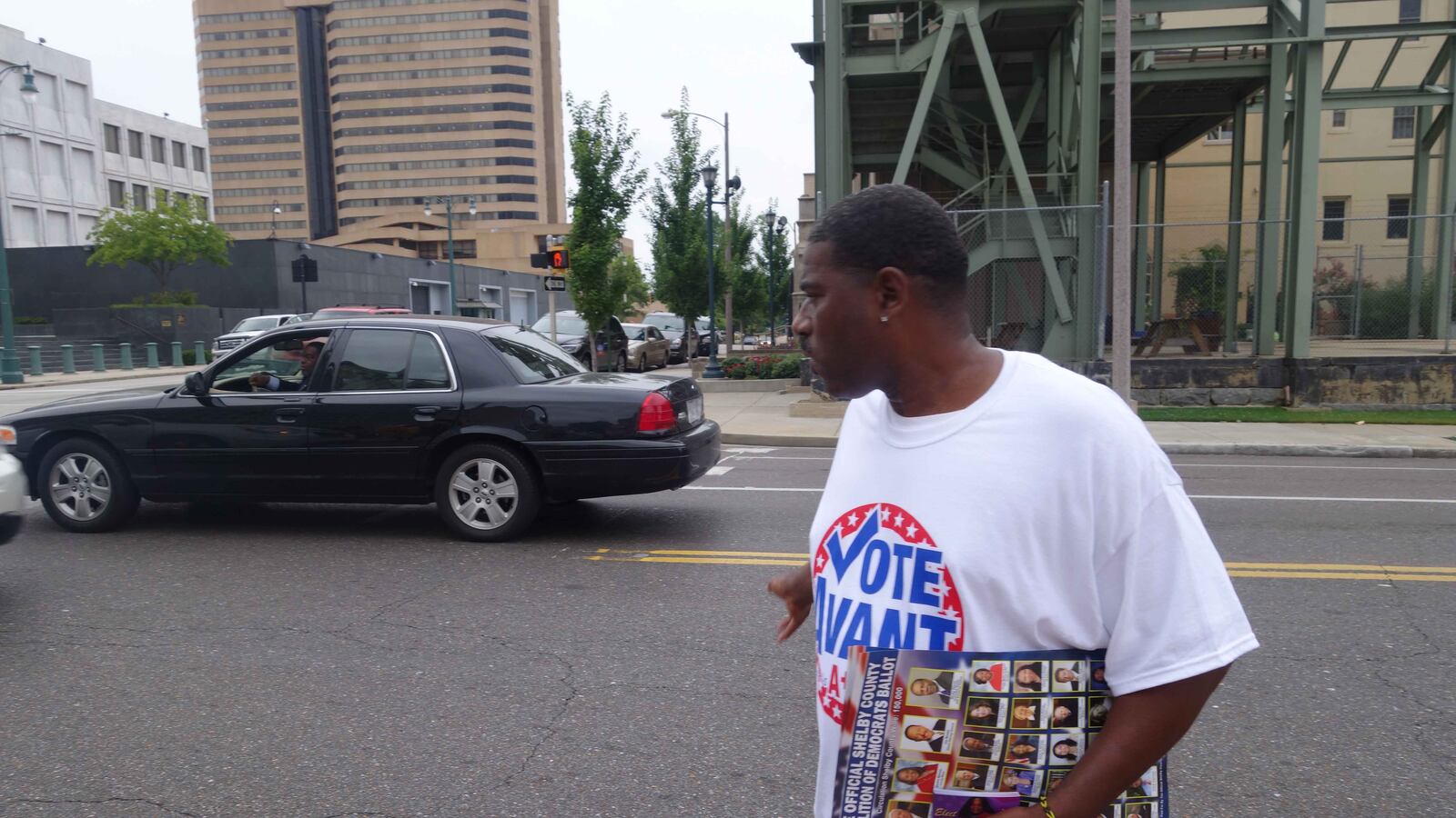 Warren Cox, a poll worker for Shante Avant, returns to the sidewalk after asking for the vote of a man waiting at a stoplight on the first day of early voting.