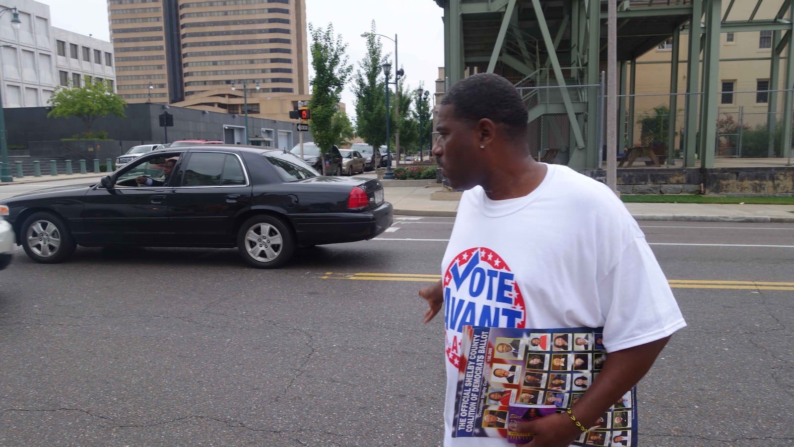 Warren Cox, a poll worker for Shante Avant, returns to the sidewalk after asking for the vote of a man waiting at a stoplight on the first day of early voting.