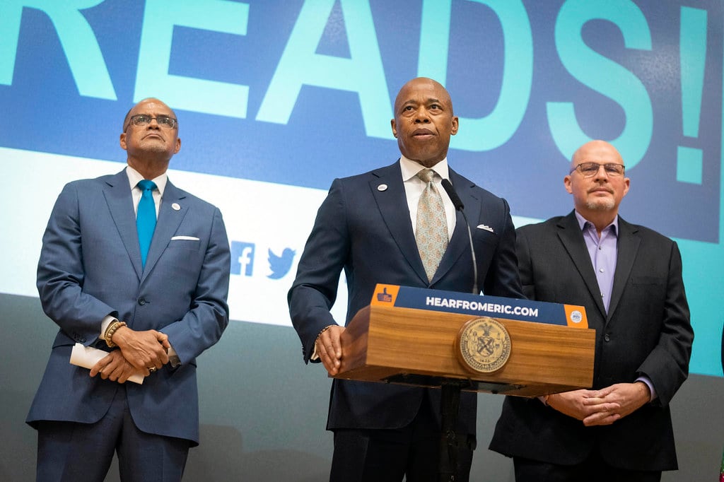 three men stand at a podium in suits