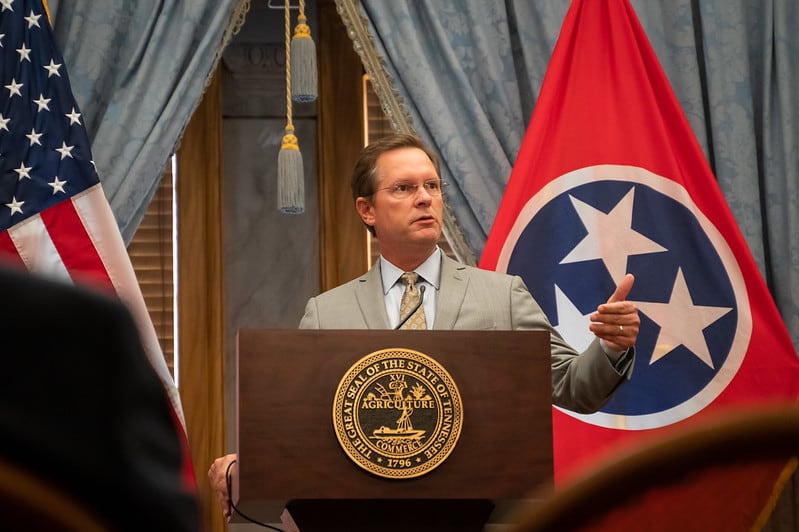 man wearing a business suit stands at a podium