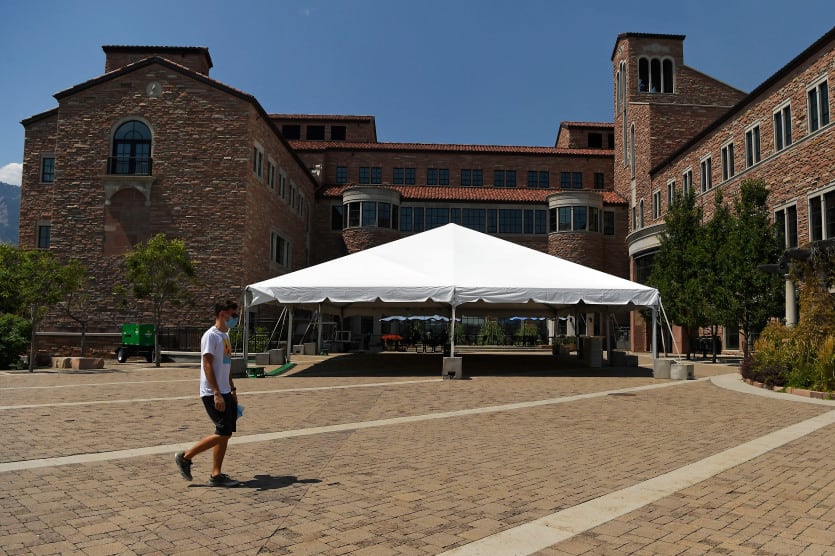 Young man walks across plaza outside the center for community complex at University of Colorado Boulder.