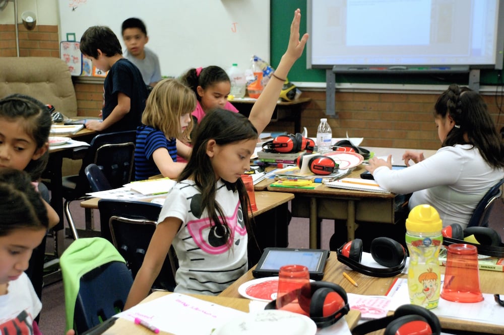 A student at Lumberg Elementary School in Edgewater raises her hand for assistance while students work on their iPads.