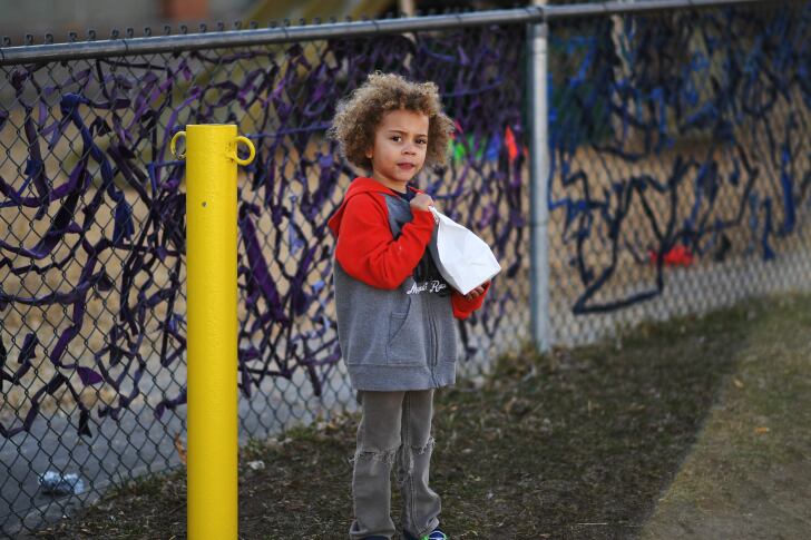 Child holds a sack lunch at a Denver grab-and-go meal site.