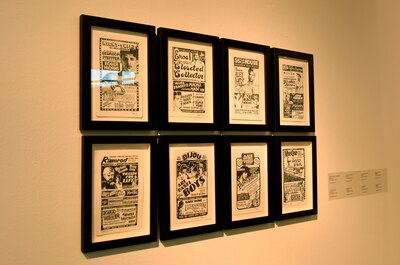 Eight pieces of art the same size and in the same black frames hang on the same wall.