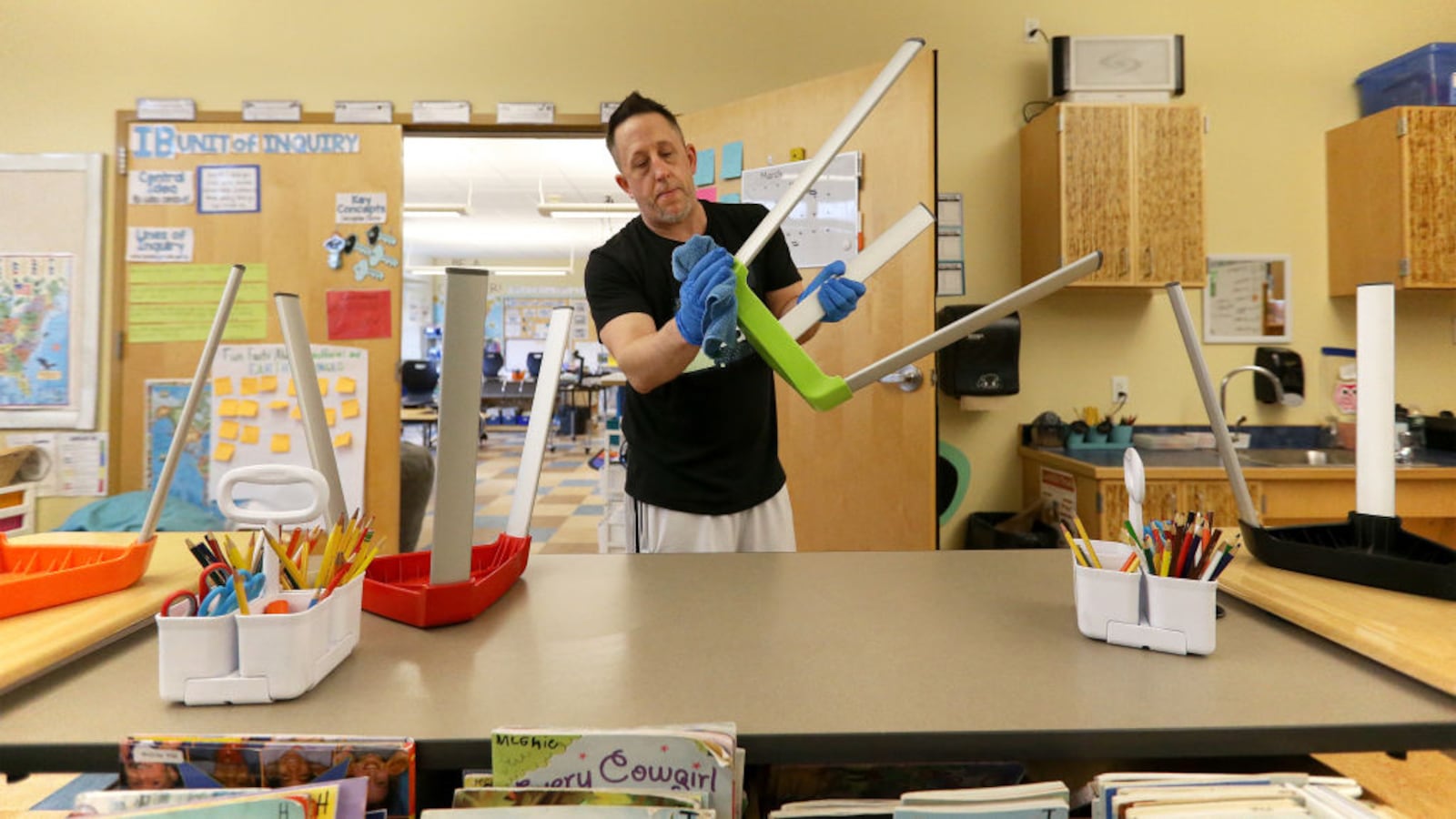 PORTLAND, ME - MARCH 6: Joseph Miller, a custodian at Ocean Avenue Elementary School, uses a disinfectant-soaked towel to clean a chair and other "touch areas" throughout a classroom. (Staff photo by Ben McCanna/Portland Press Herald via Getty Images)