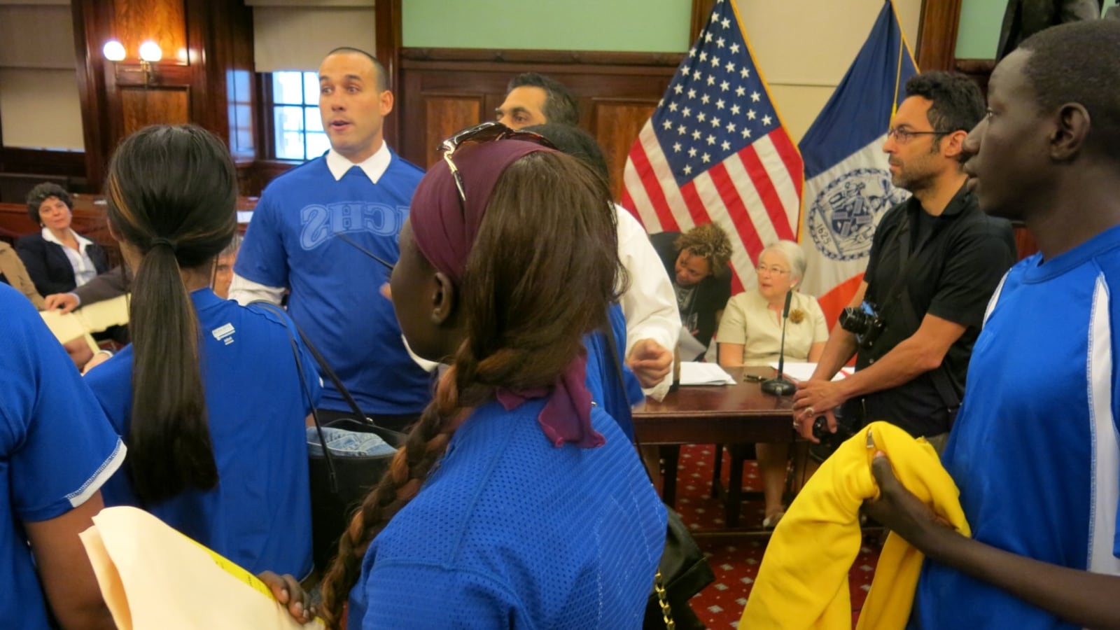 David Garcia-Rosen (left, wearing a white shirt collar and blue jersey), founder of the Small Schools Athletic League, marched into a City Council hearing with student athletes to demand funding for the league.