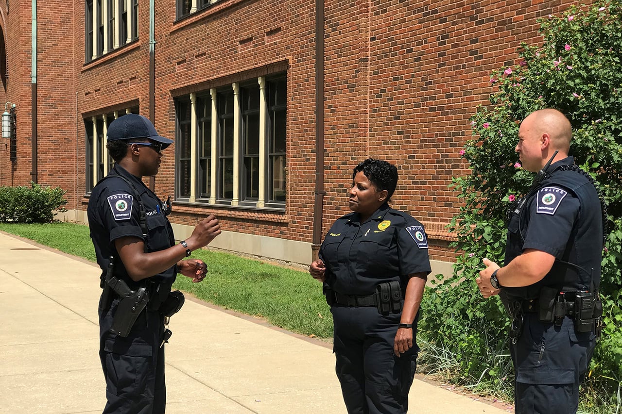 Indianapolis Public Schools Police Department Chief Tonia Guynn talks to two other officers working for the district in front of a school building.
