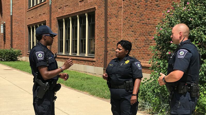 Indianapolis Public Schools Police Department Chief Tonia Guynn talks to two other officers working for the district in front of a school building.