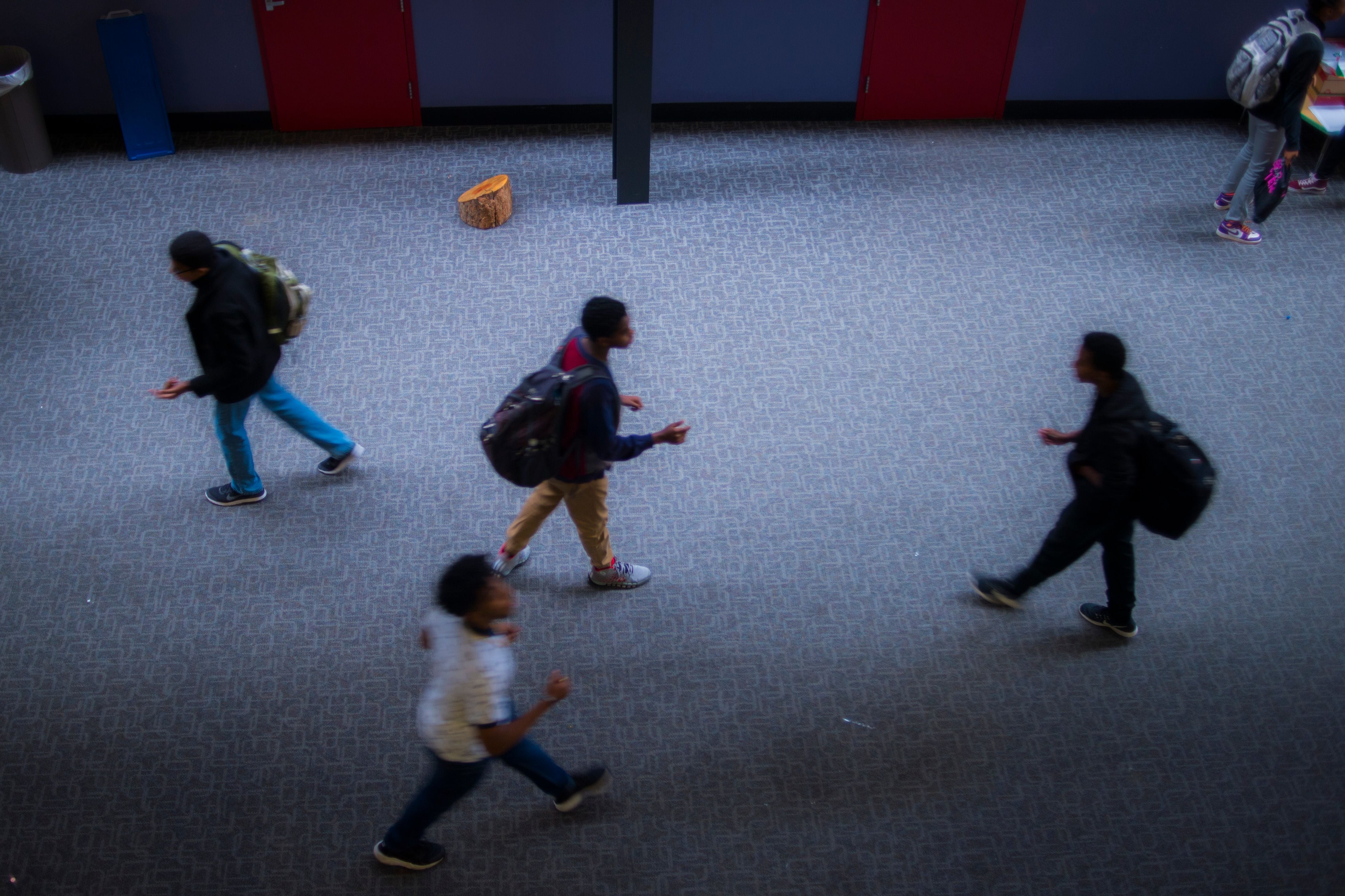 A blur of students walk through a hallway.