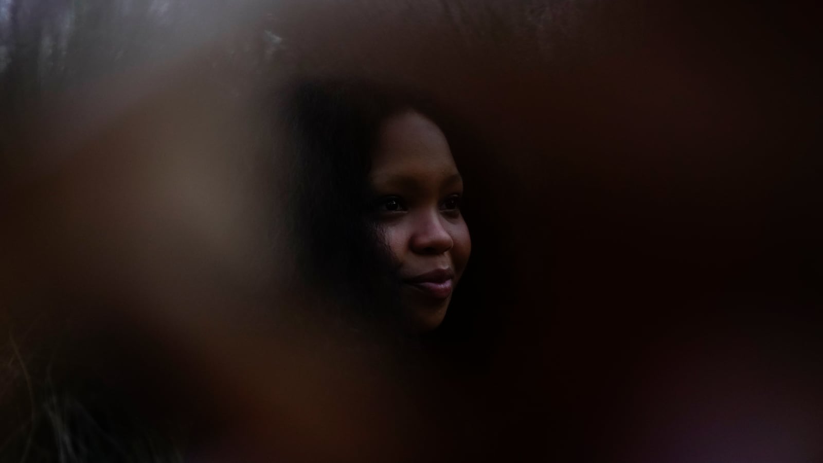 A young woman poses for a portrait amidst a swirl of foreground and background blur.