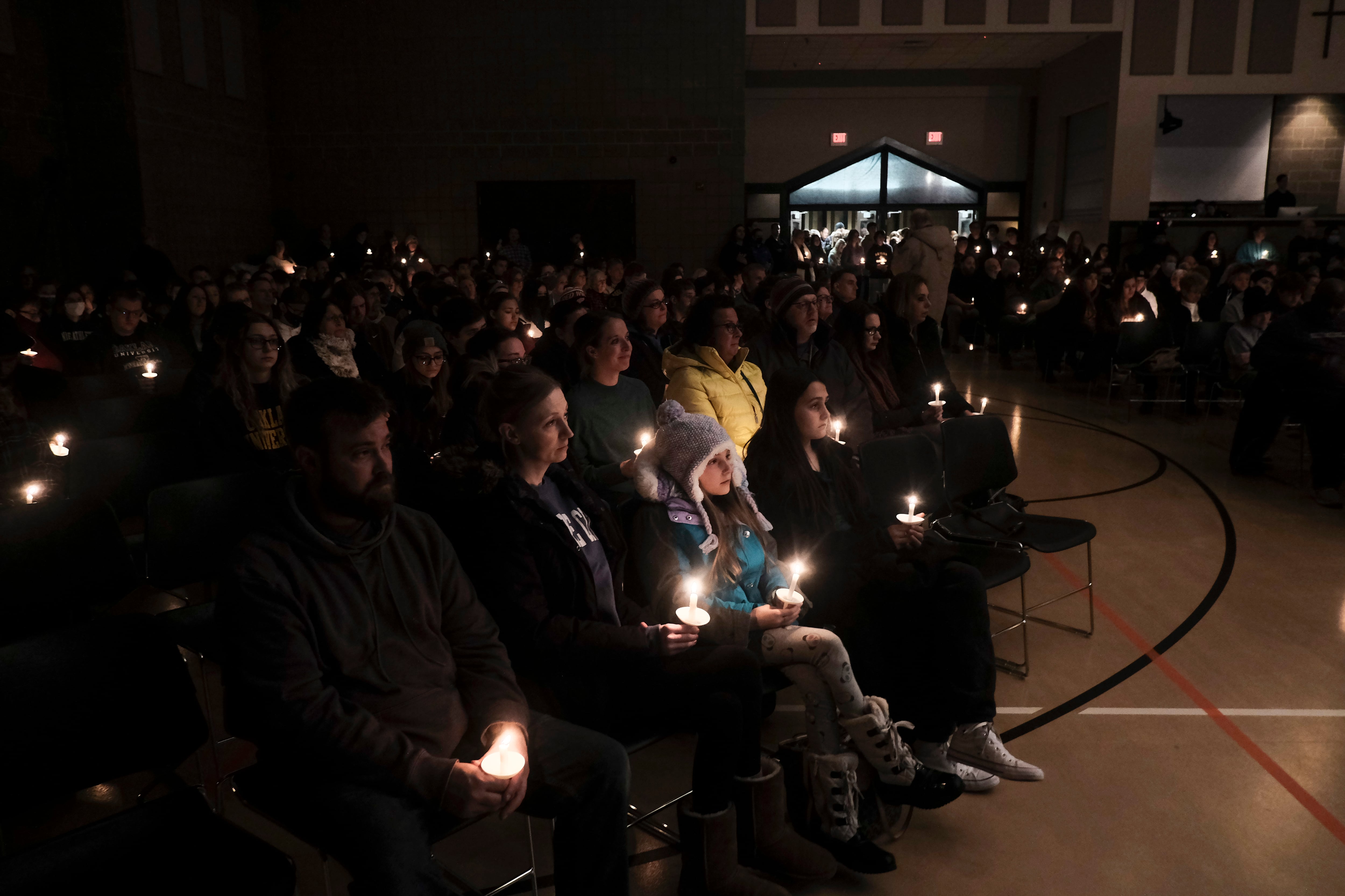Scores of students, teachers, parents, and community members hold a candlelight vigil following a school shooting.