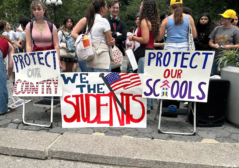 Students hold protest signs.