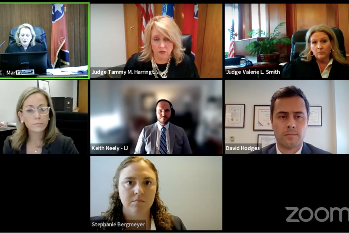 Three robed judges and others in business suits hold a Zoom meeting.