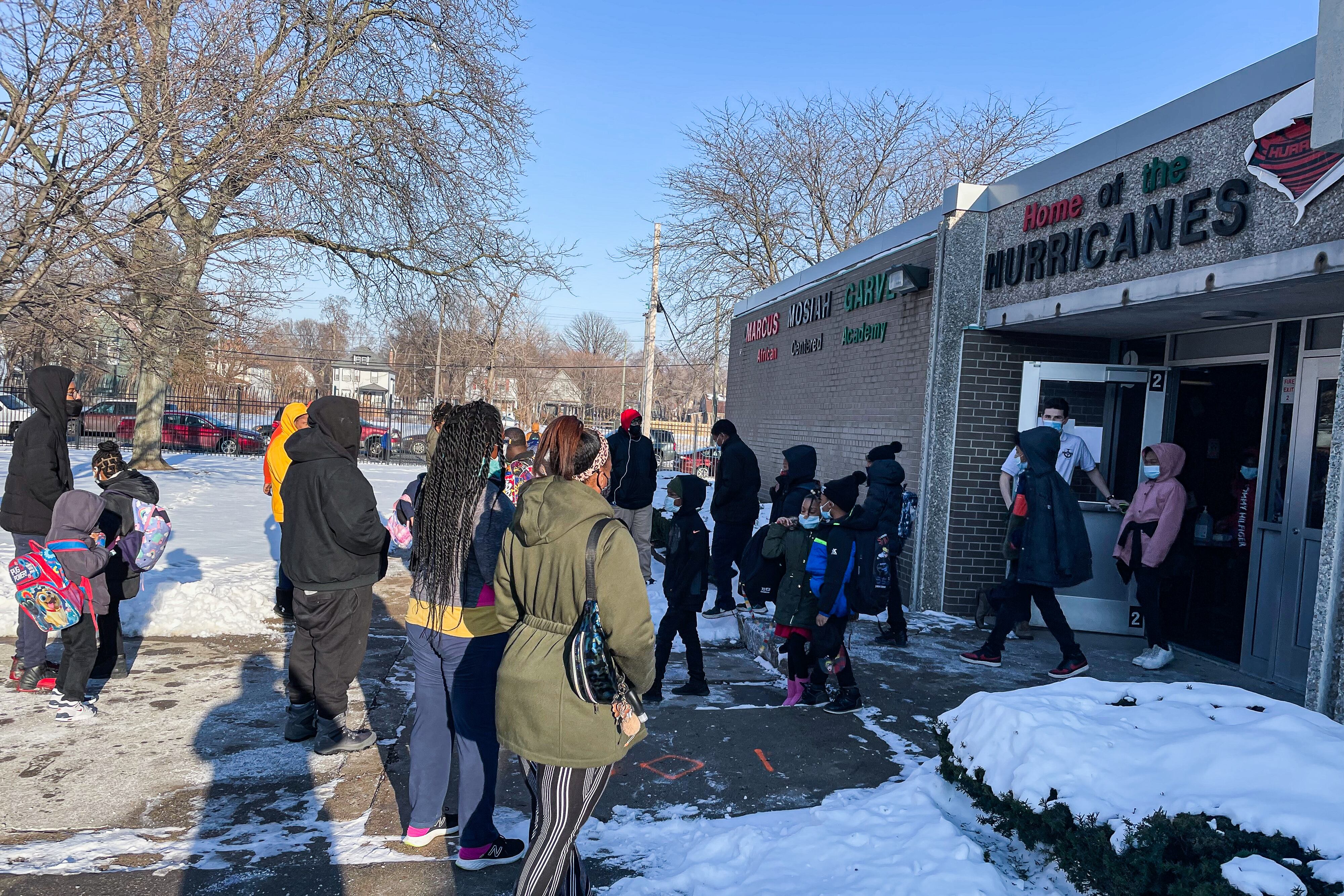 Parents pick up their young students from school on a sunny winter day.