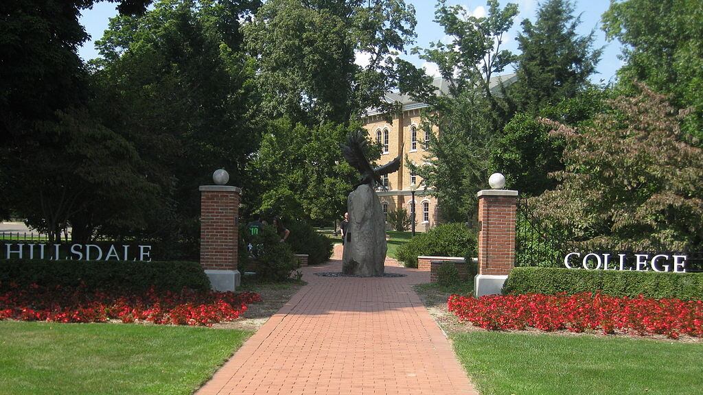 Open entrance gate to a college campus with bricked walkway that leads to a courtyard with a bronze statue of an eagle