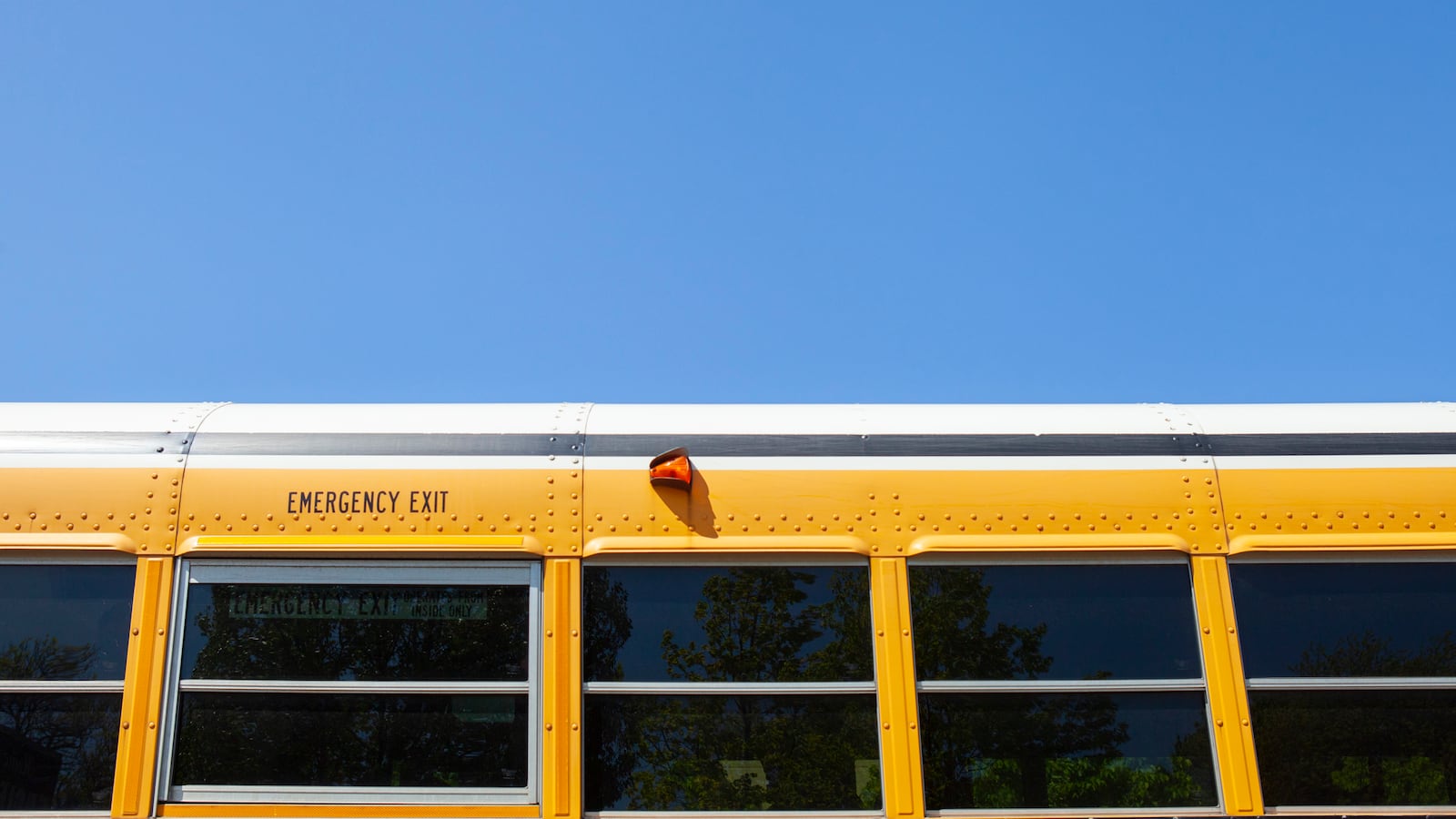 The top of a school bus splits is pictured against a bright blue sky.