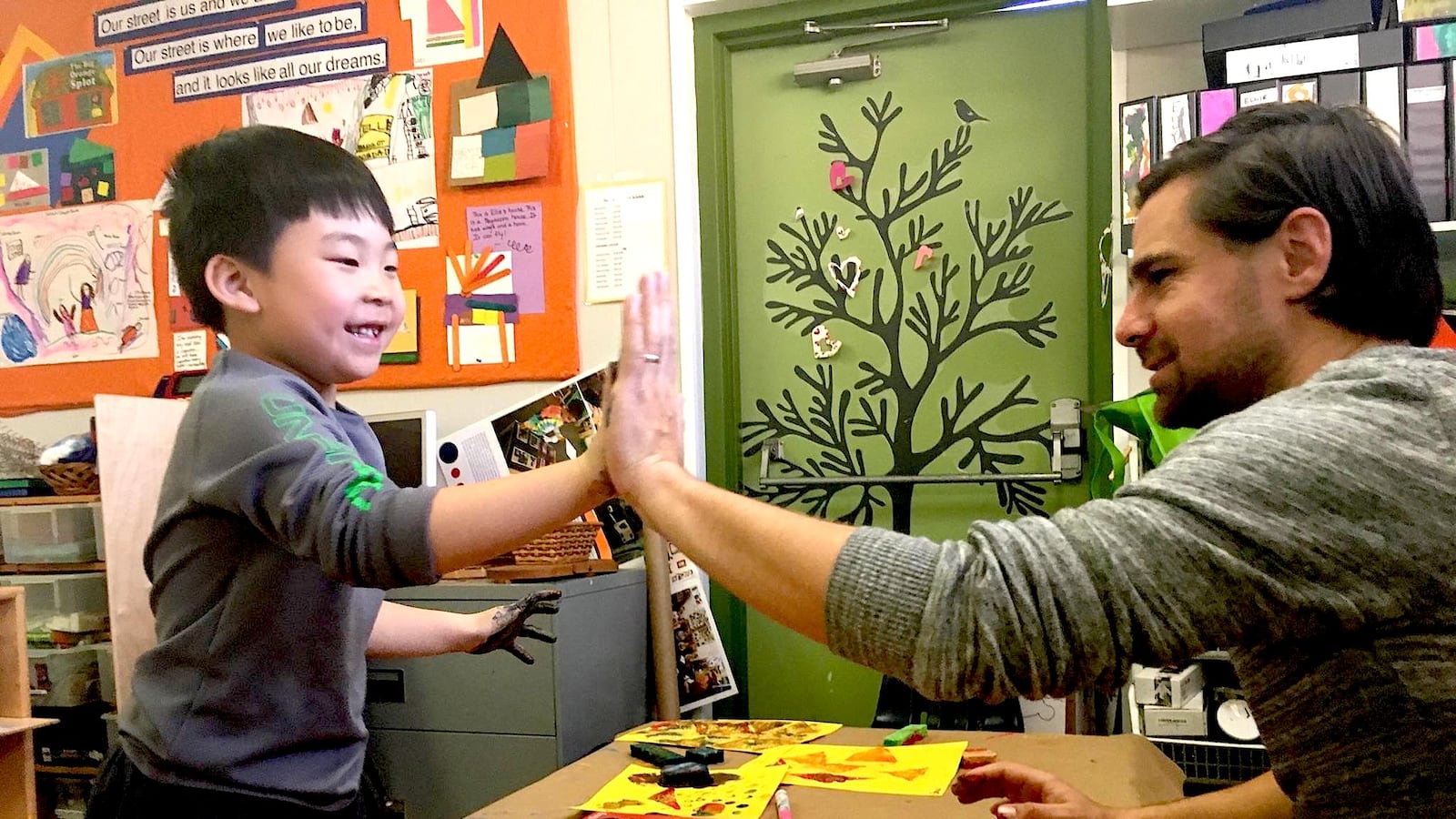Graham Carson, a teacher at Denver Cooperative Preschool, finger paints with a student.