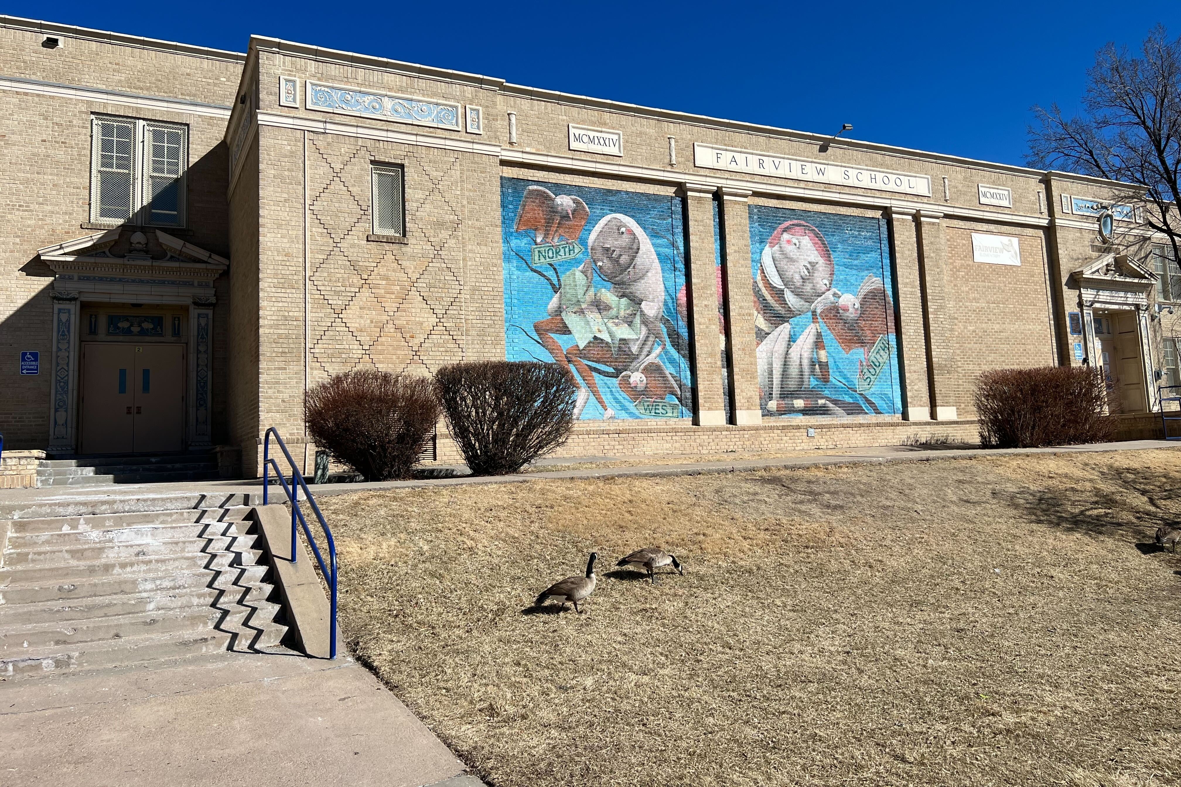 Exterior image of Fairview Elementary shows a short stairway, mosaic tile, and colorful murals.