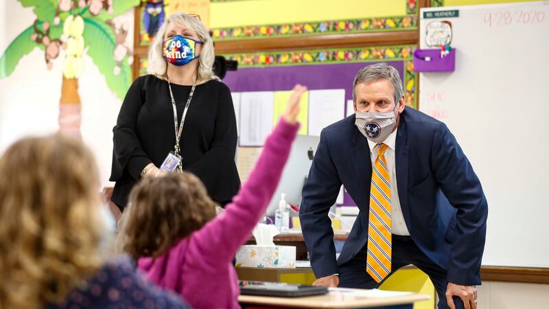 Gov. Bill Lee squats to talk to elementary students at the front of the classroom while students raise their hands.