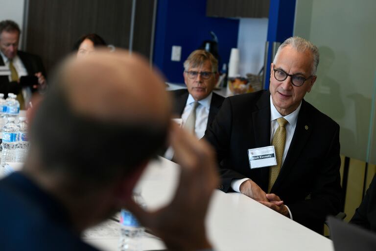 University of Colorado President Mark Kennedy, wearing a suit, sits at a table with other people.
