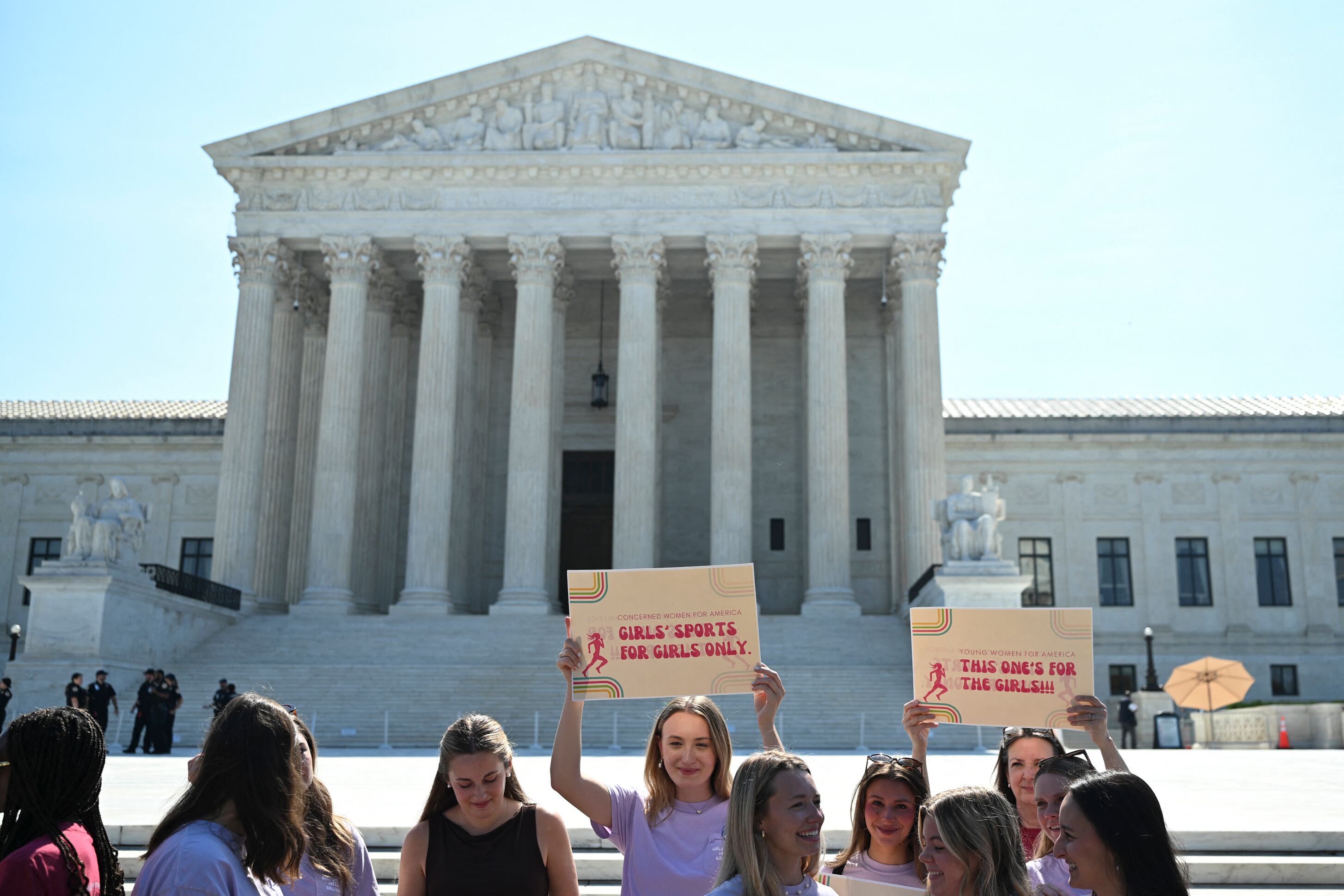 A photograph of a group of young women outside the US Supreme Court holding signs that read "Girls' sports for girls only."