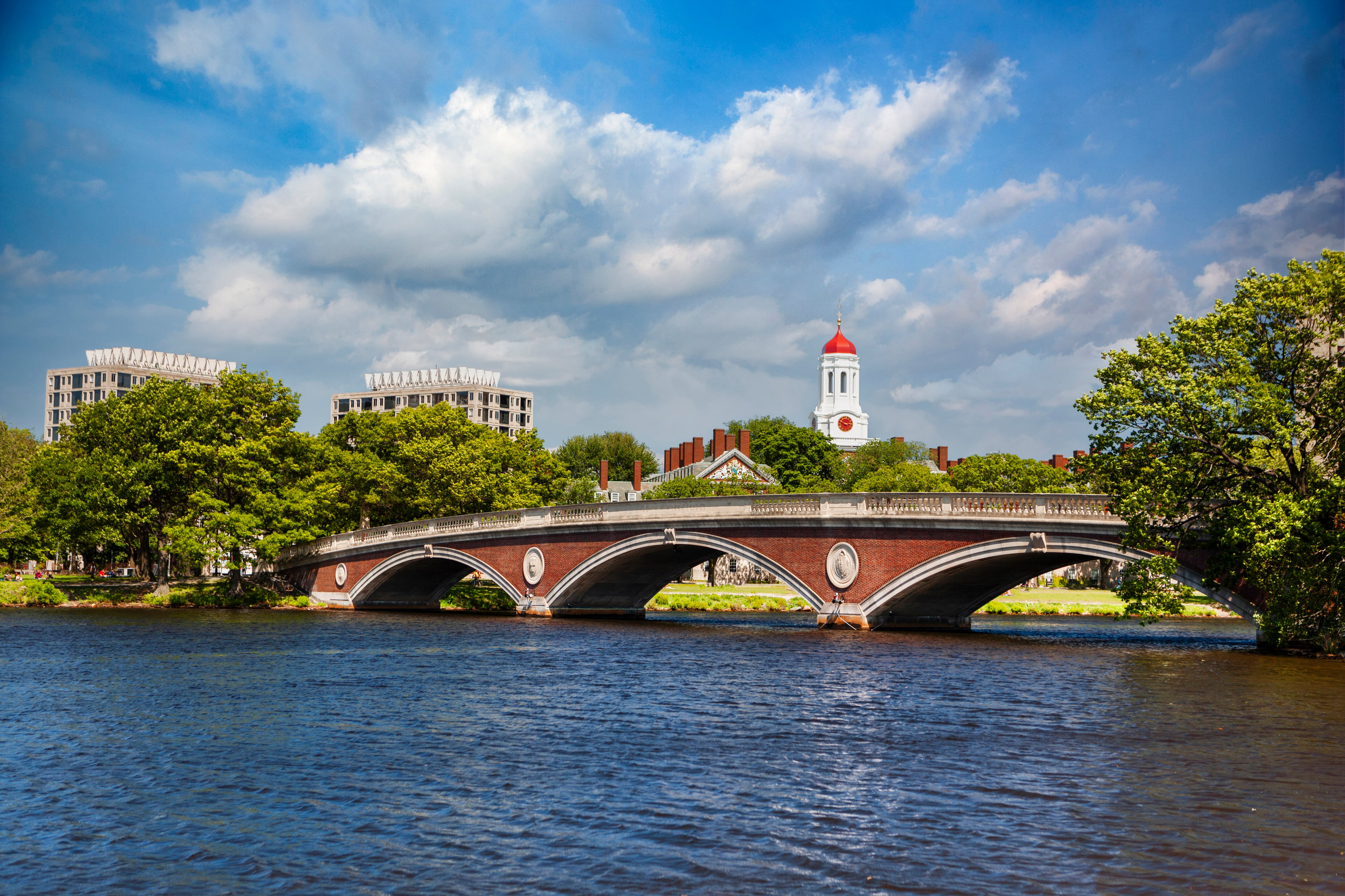 A bridge crosses a river in front of a building with a dome.