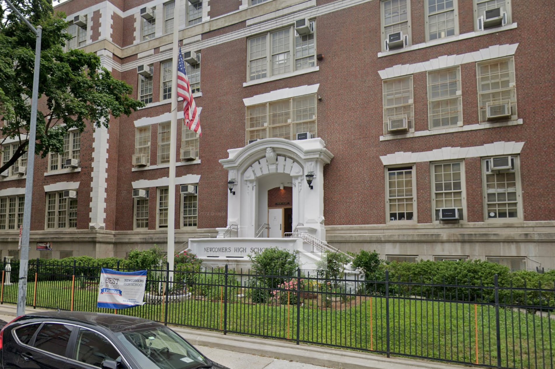 A brown brick building with a white entrance and an American flag in the foreground.