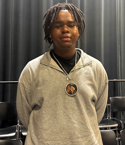 A portrait of a teenager in a light sweater and black top.