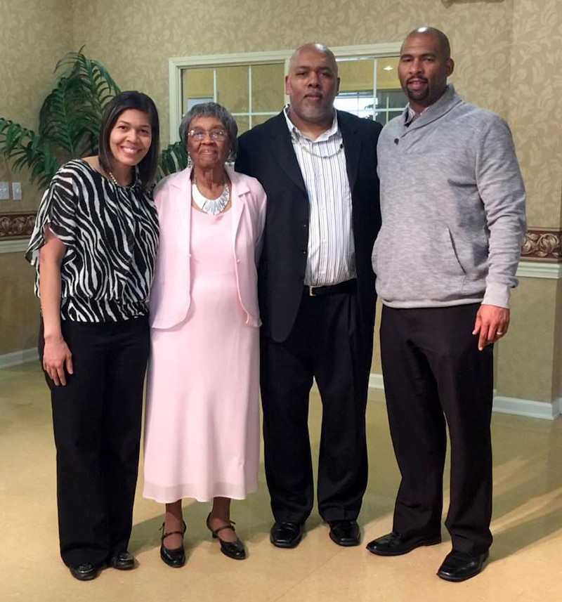 A photograph of two Black women standing next to two Black men all posing for a photograph.