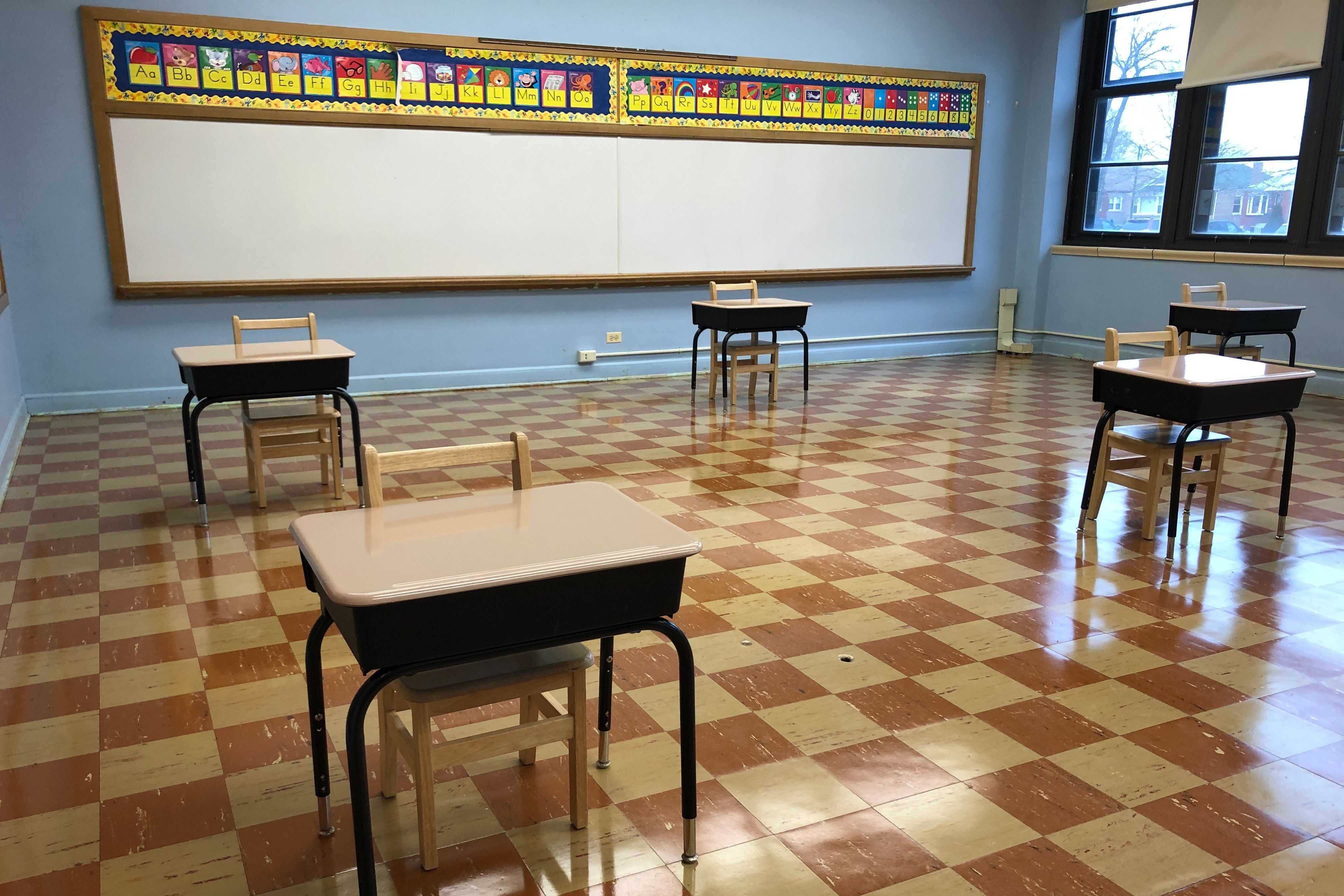 An empty classroom with desks spaced out six feet apart.