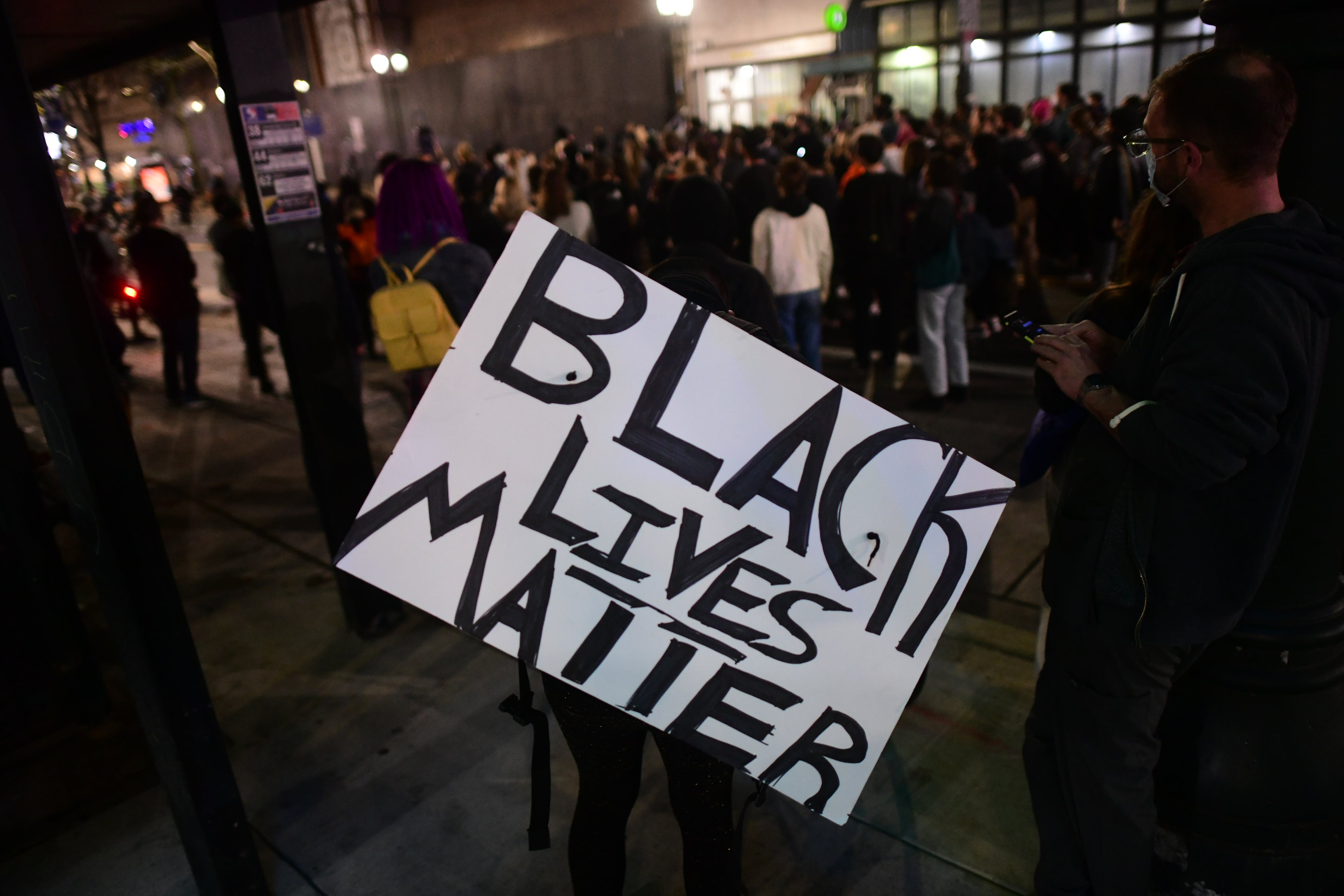 A man holds a sign surrounded by others.