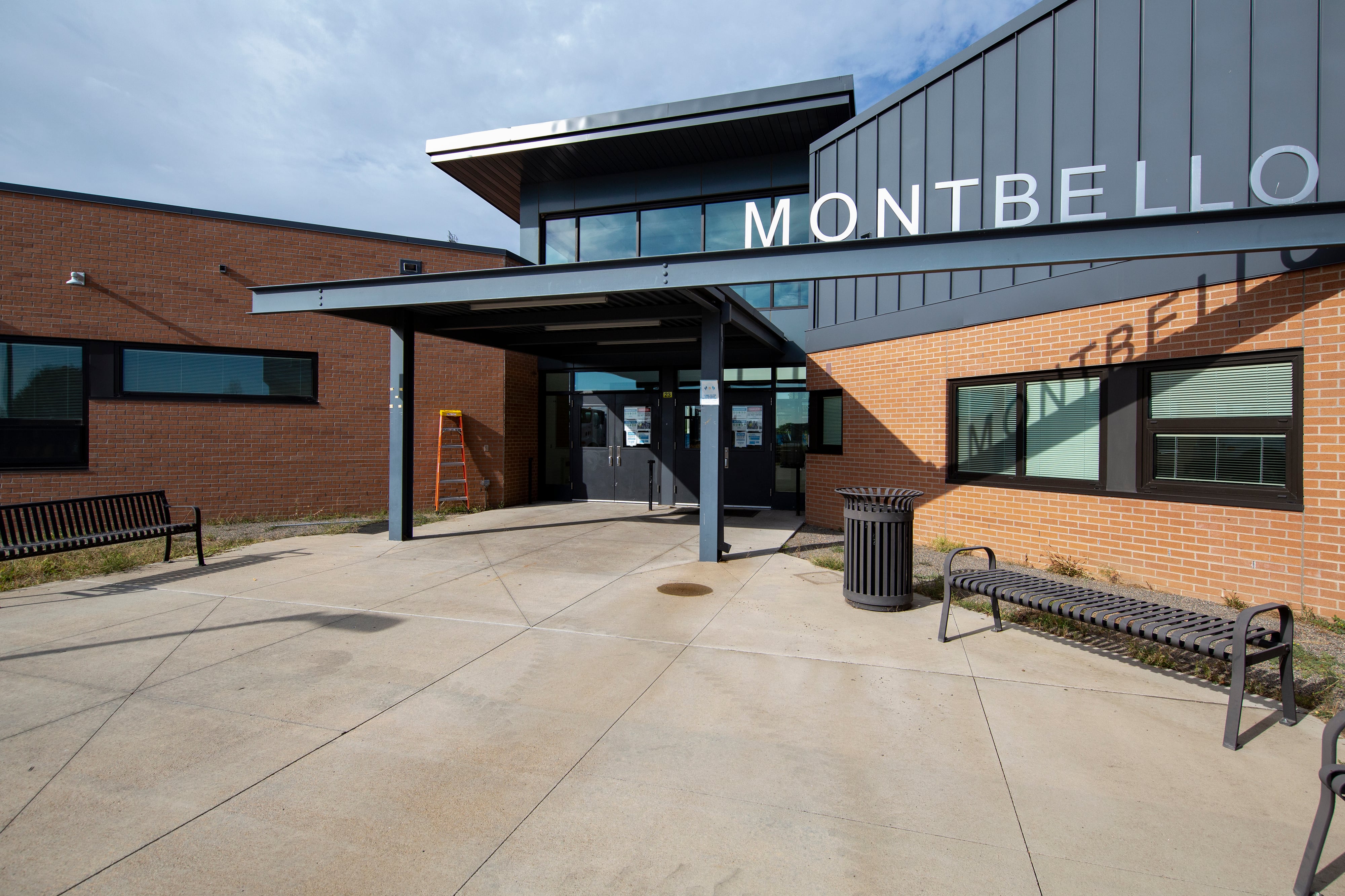 The facade of Montbello High School in Denver, the letters on an awning casting a shadow on a brick wall and its windows.