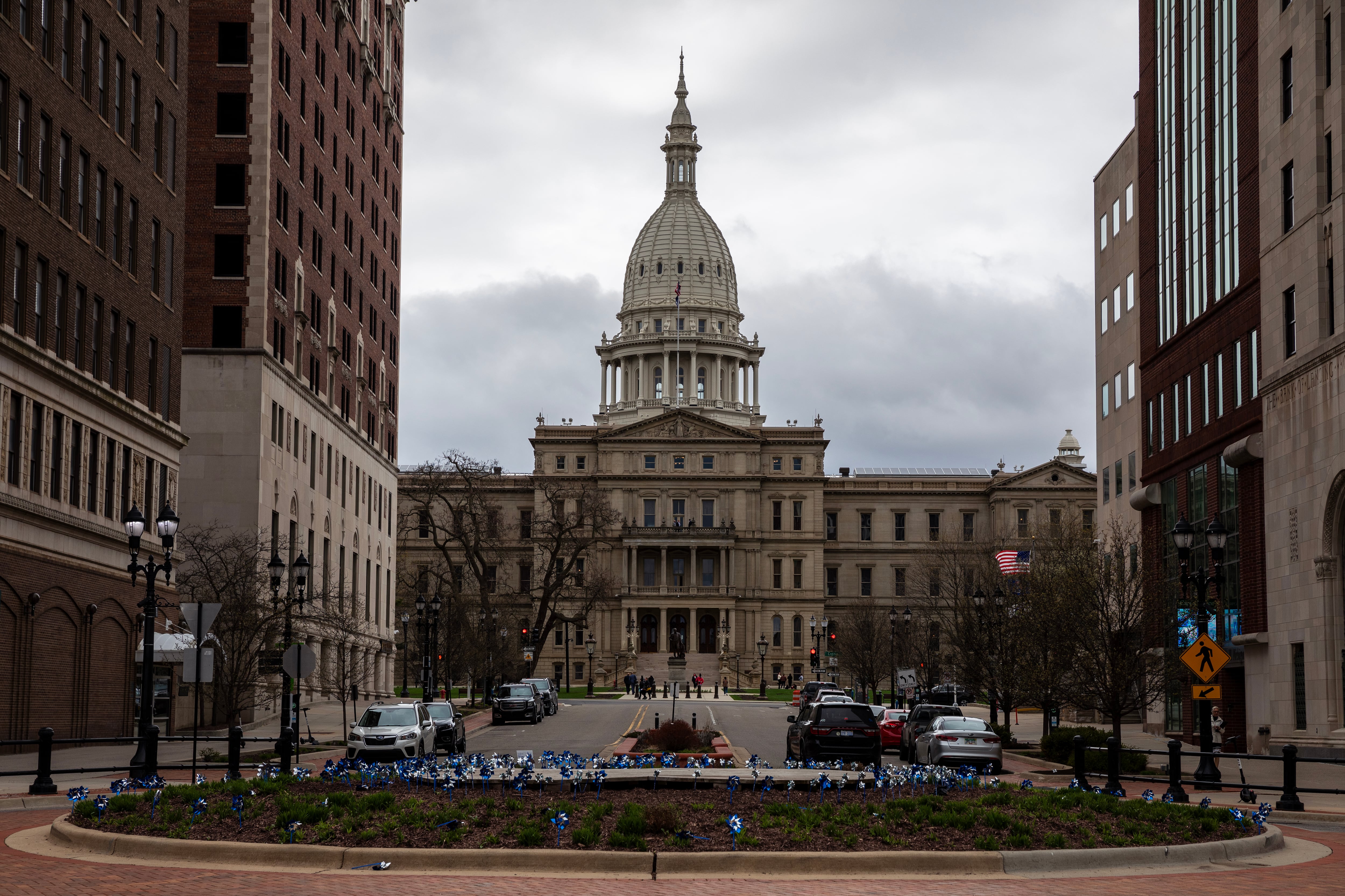 A wide view of the Michigan State Capitol building with a cloudy sky behind.