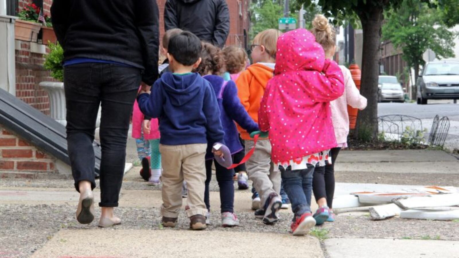 A group of small children are led by a caregiver down a Philadelphia street.