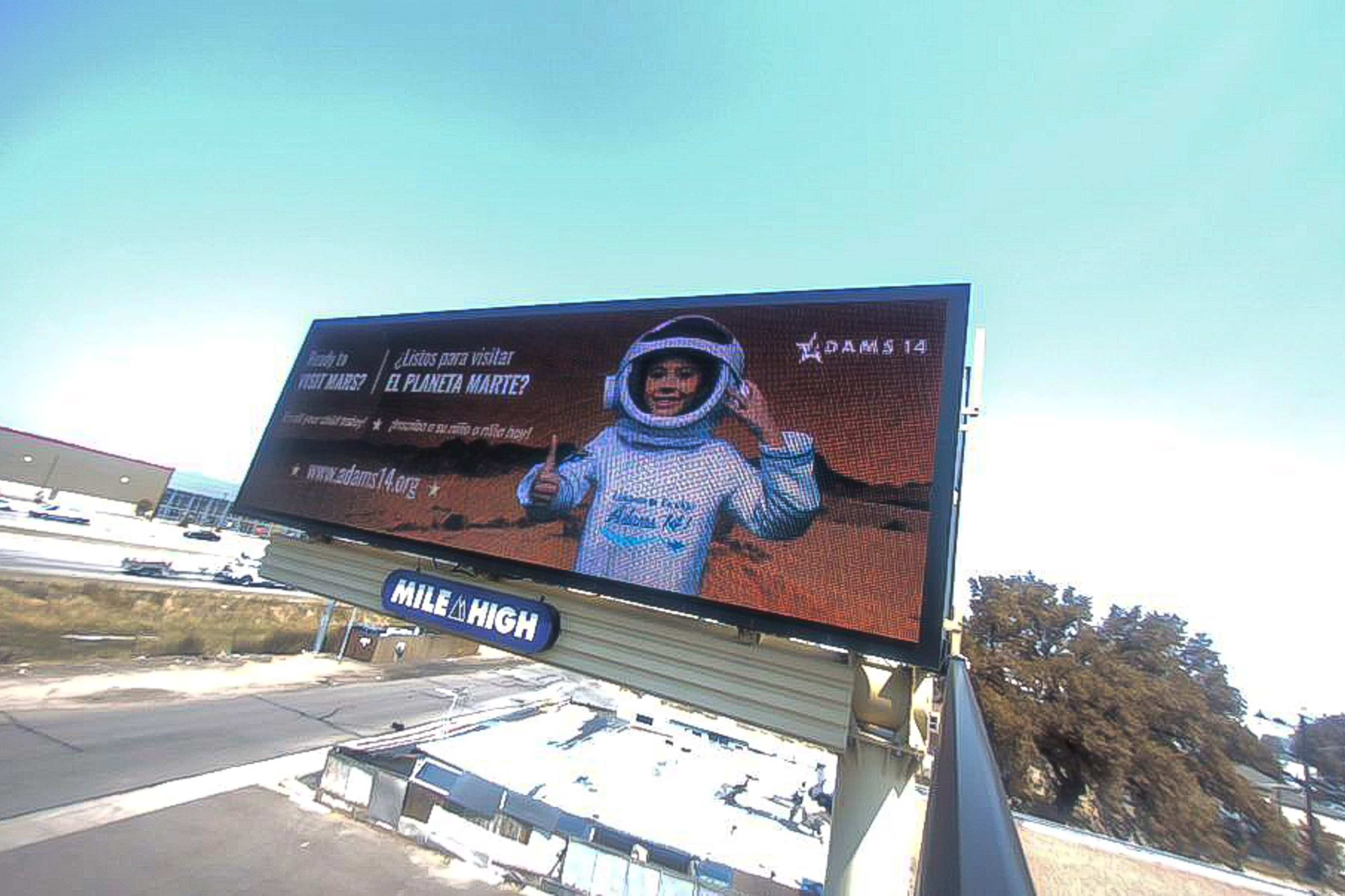 A billboard for Adams 14 School District shows a child as an astronaut with the text “Ready to visit Mars?” on the left-hand side in English and Spanish.