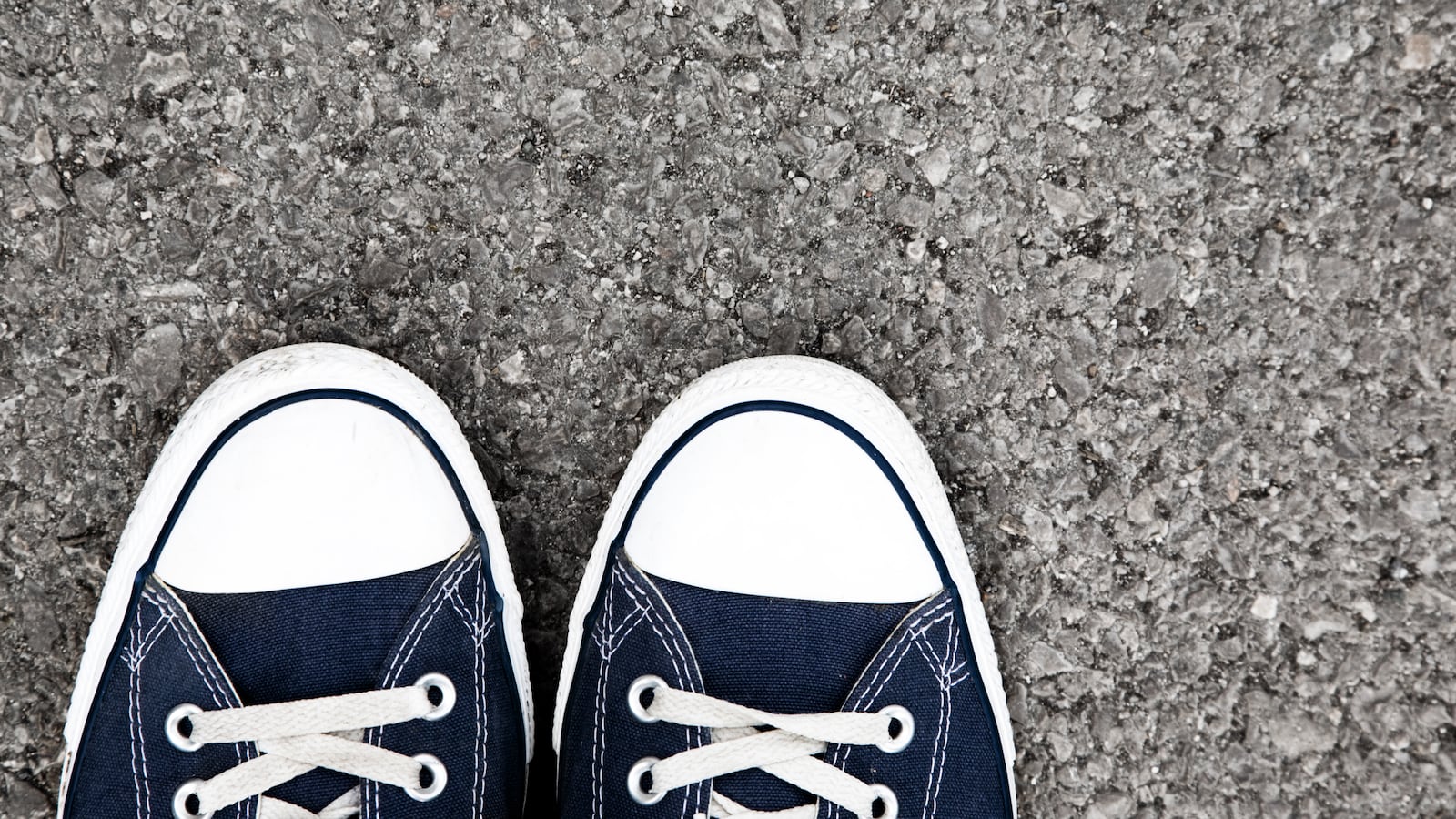 A pair of black Converse sneakers on asphalt
