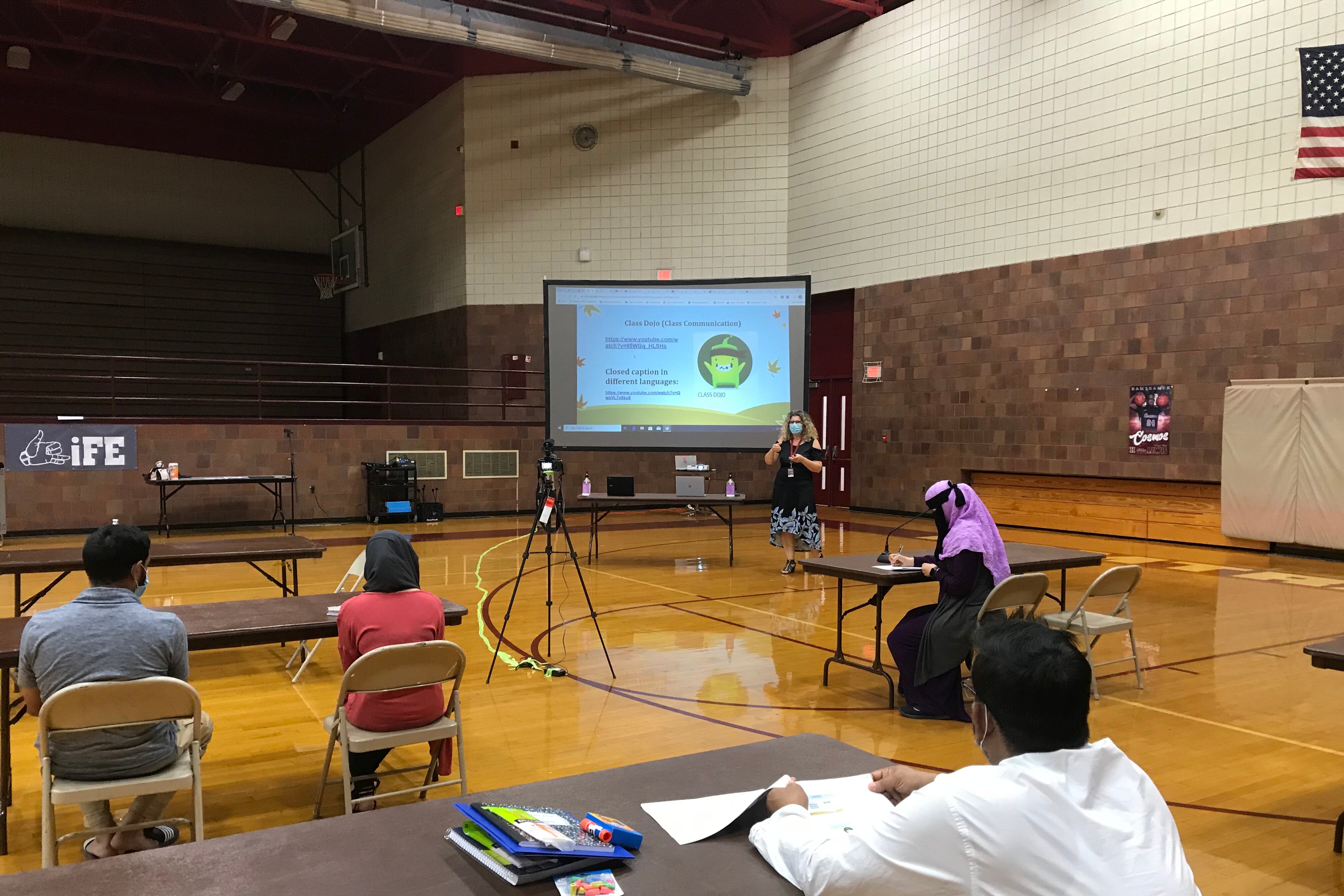 English learners and their parents sit at a social distance in a Hamtramck gym during the coronavirus pandemic to learn about online instruction.
