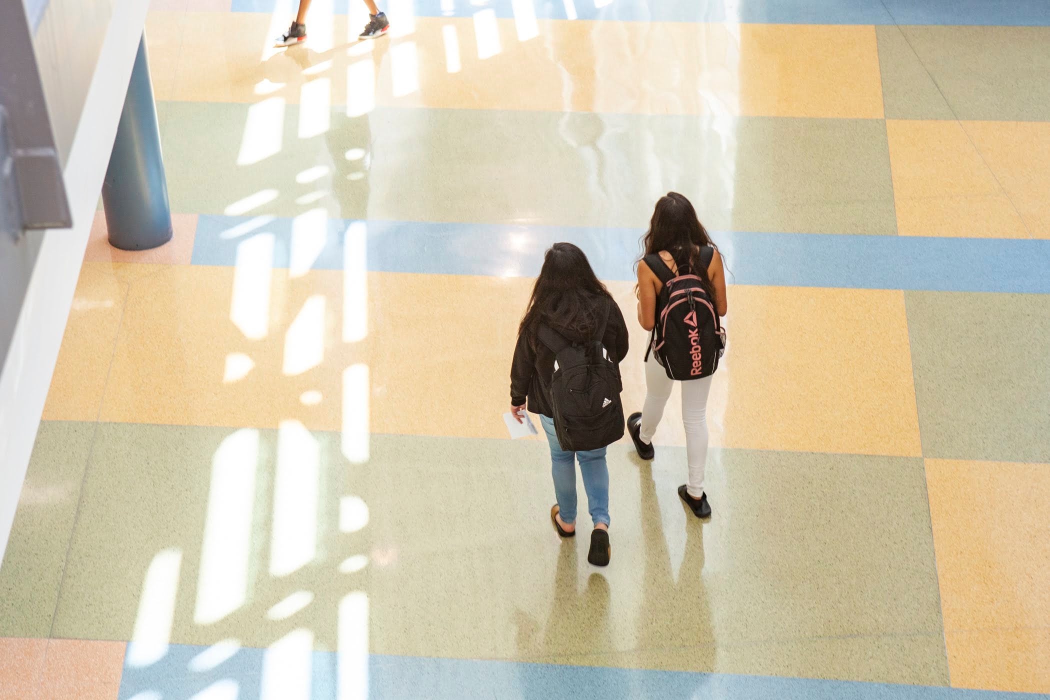 A bird's eye view of two students walking down a hallway.
