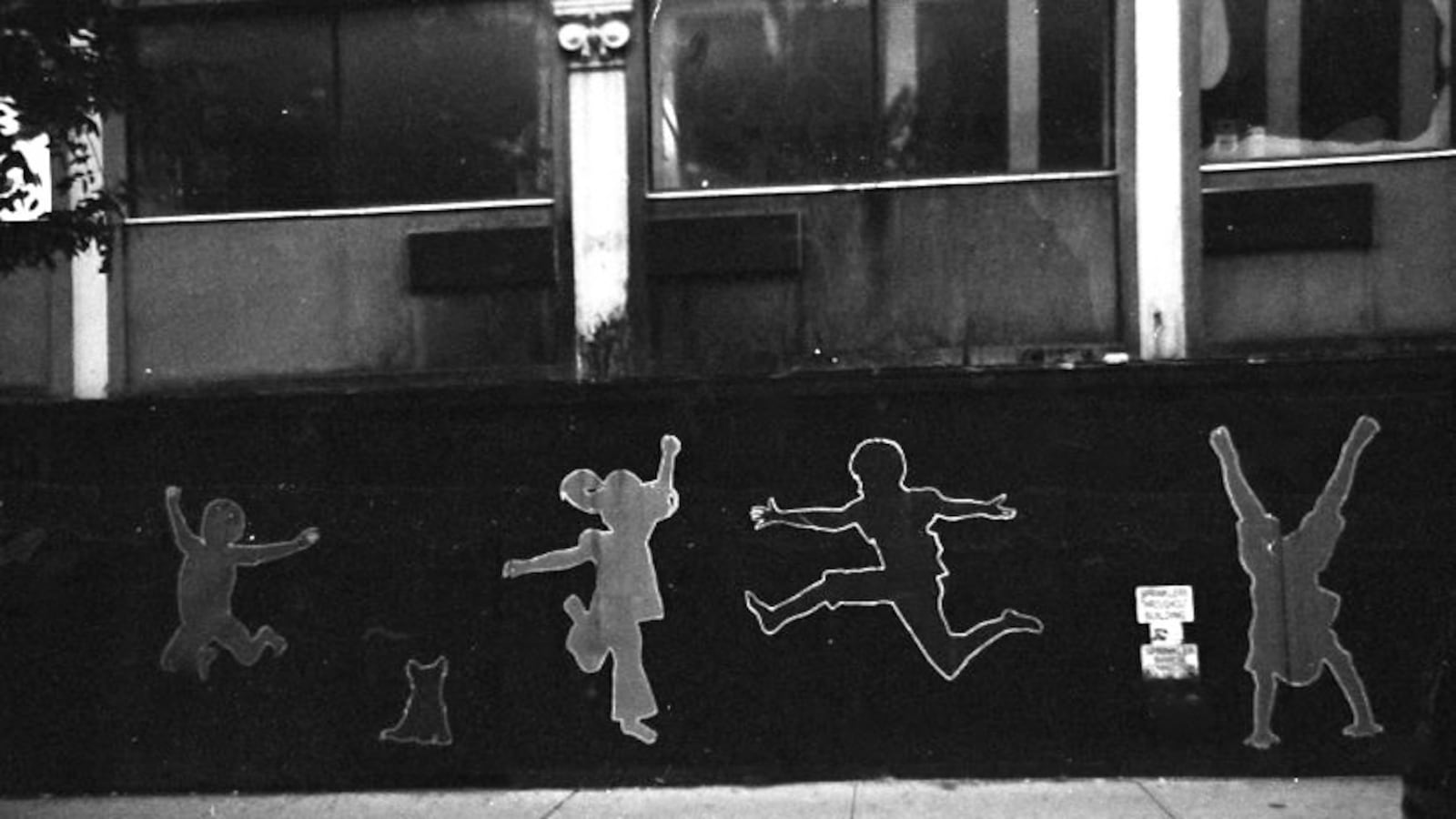 A black and white photo of a mural featuring the silhouettes of kids playing.