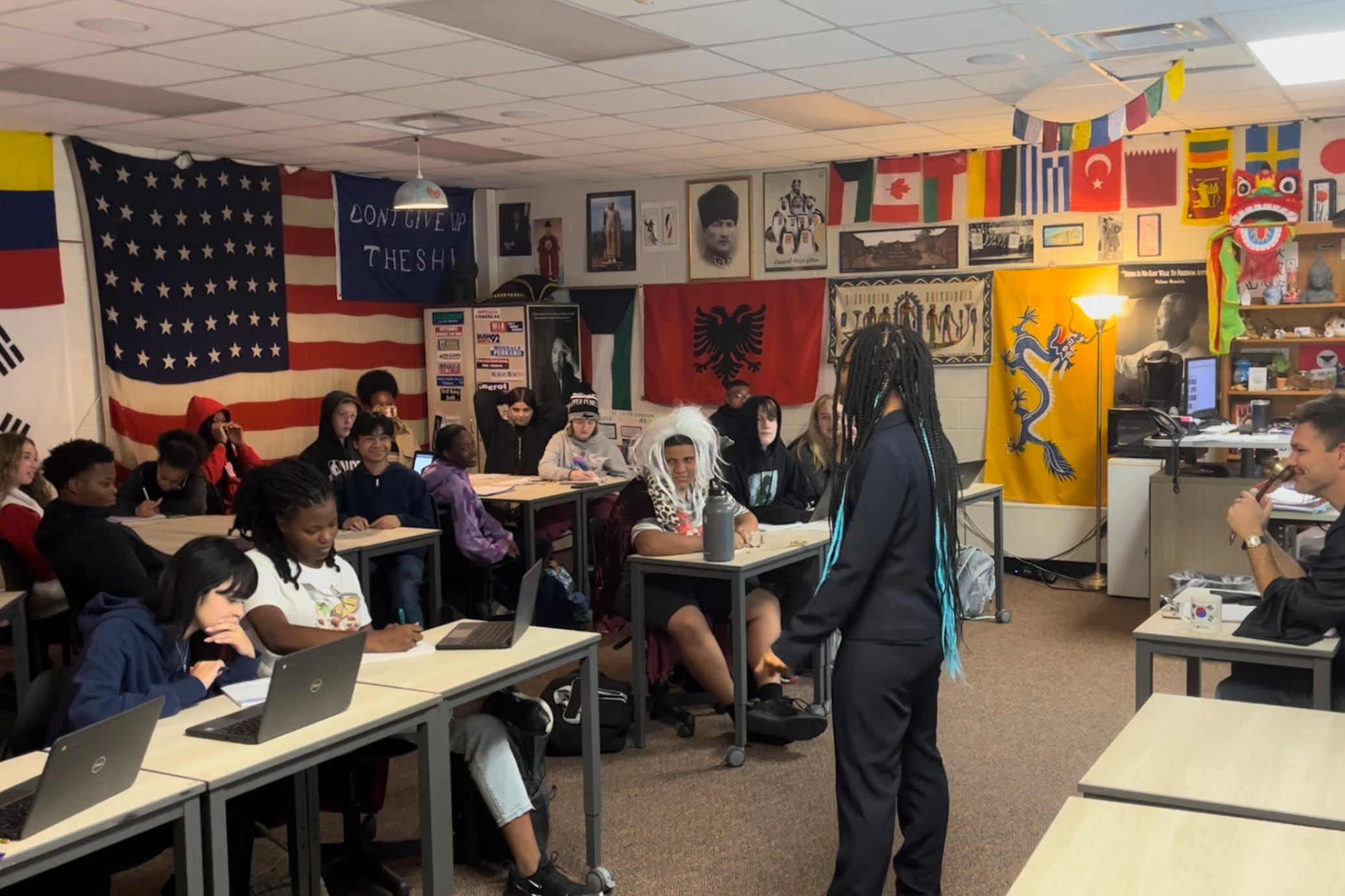 Students and a teacher sit in a classroom during a history lesson.