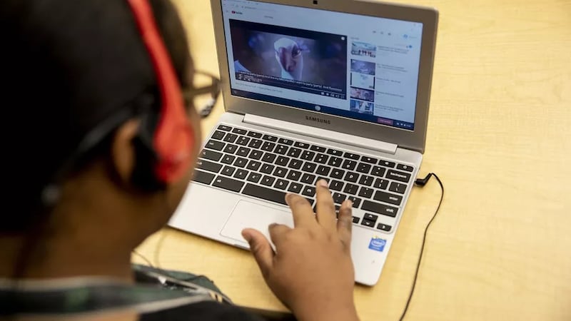 A student wearing headphones works on a laptop computer during a special education classroom exercise.