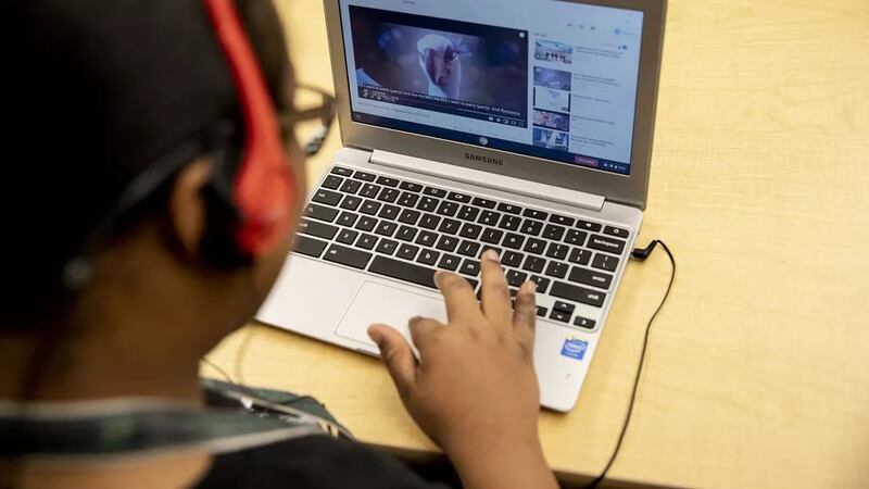 A student wearing headphones works on a laptop computer during a special education classroom exercise.