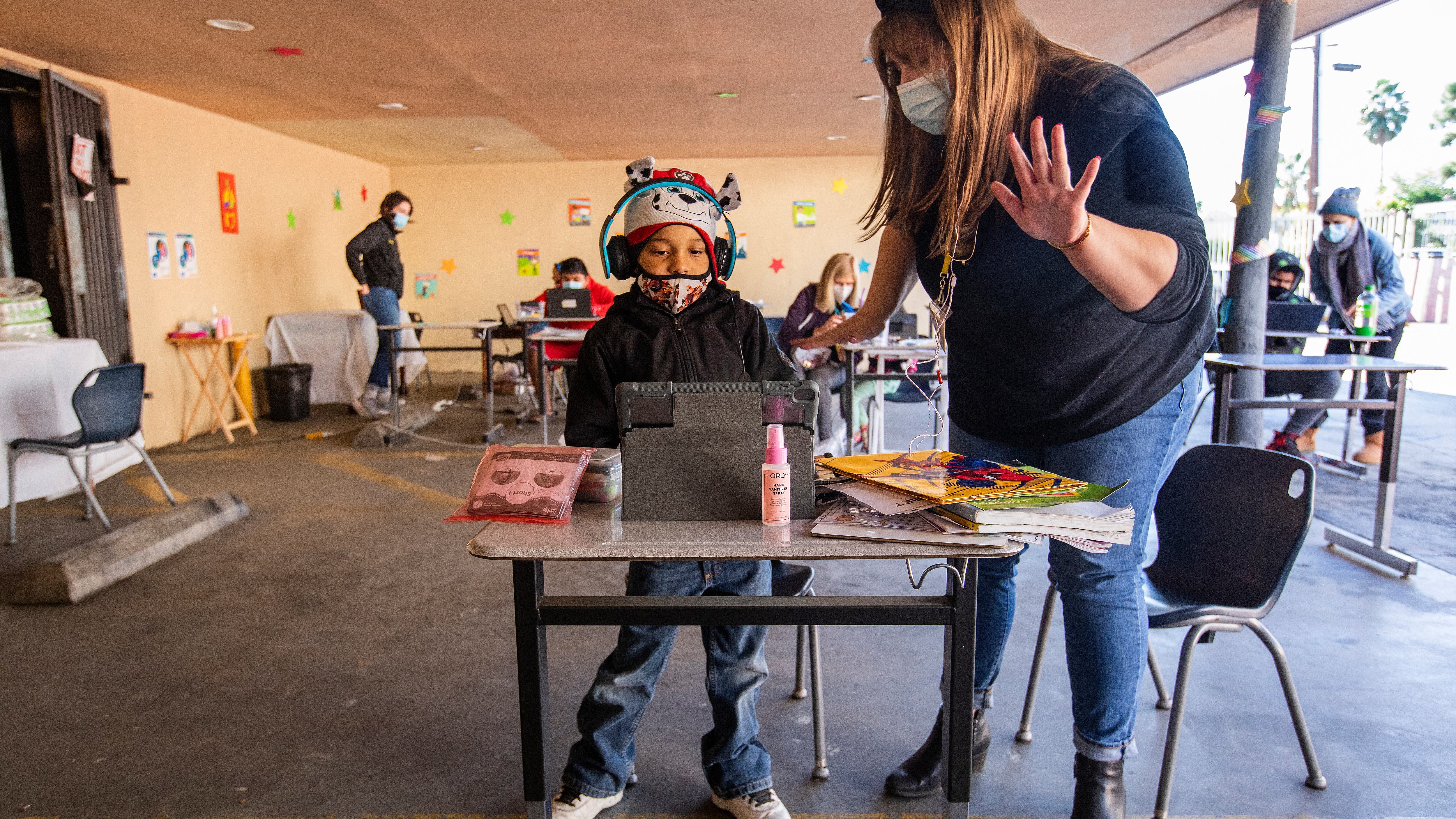 A volunteer helps a first-grade student learn math at a California learning pod for homeless children in November 2020.