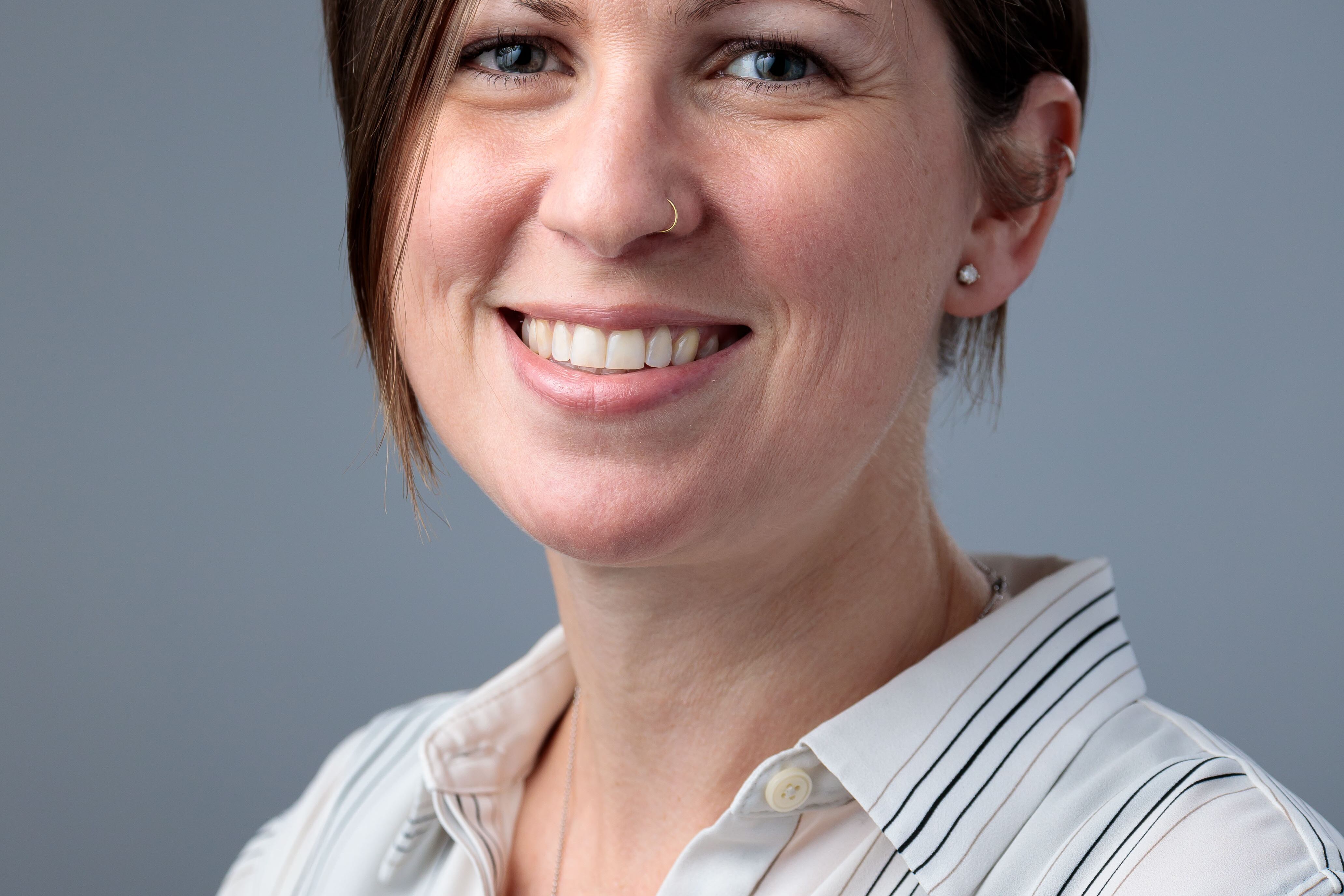 A researcher with short brown hair and a striped collared shirt poses for a headshot.