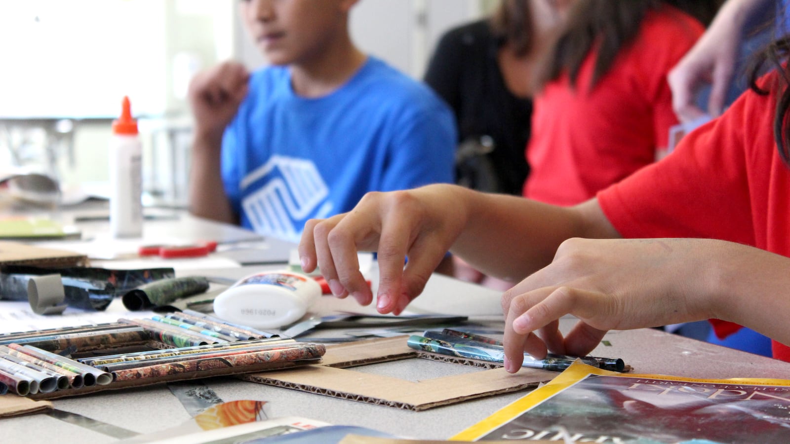 A student glues rolled up magazine pages onto a picture frame. The activity, offered by the Boys & Girls club, was all about creating "up-cyclced" art.
