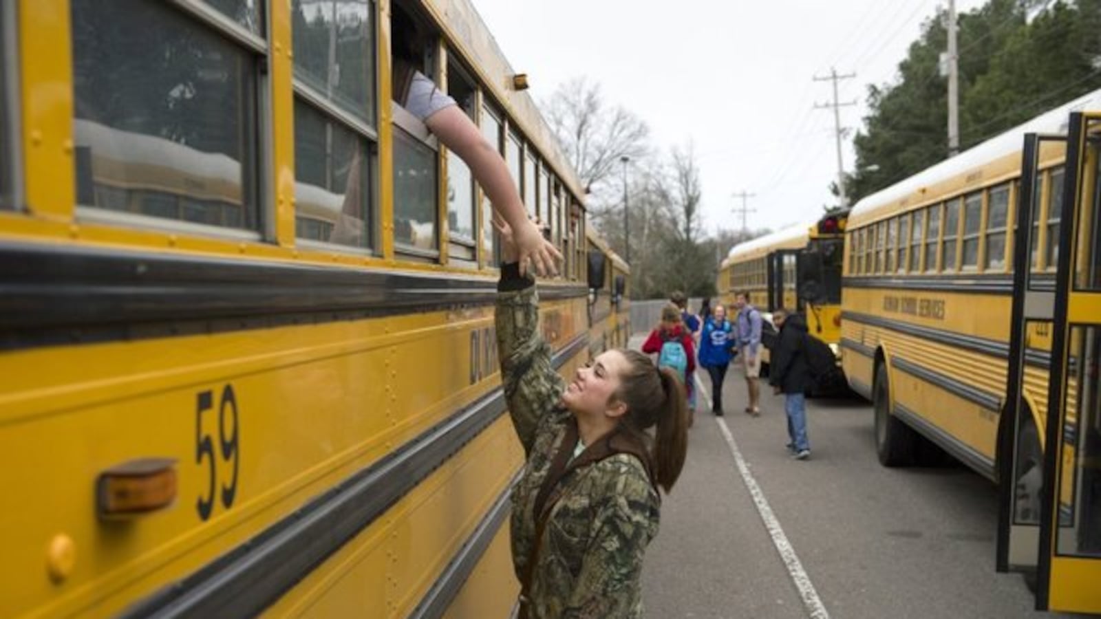 In a 2015 photo, a student says goodbye to her friend as the pair board buses for home at the end of a school day at Bartlett Ninth Grade Academy.