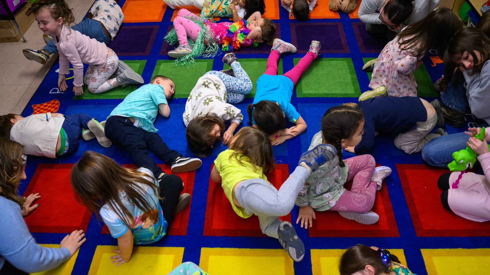 An aerial photograph of a group of young students who are resting on a colorful carpet.