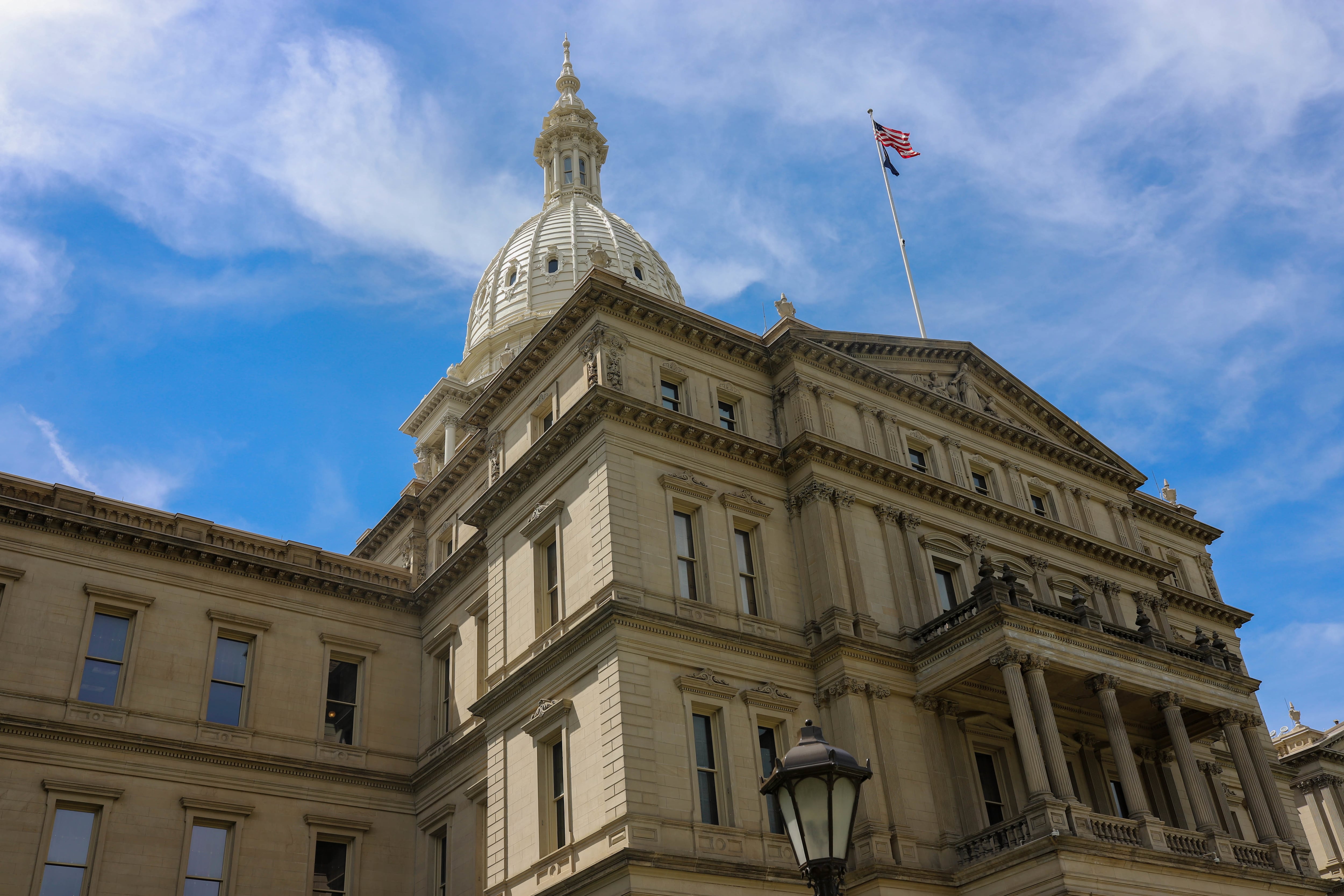 The Michigan state Capitol building in Lansing on a sunny day with wispy clouds.