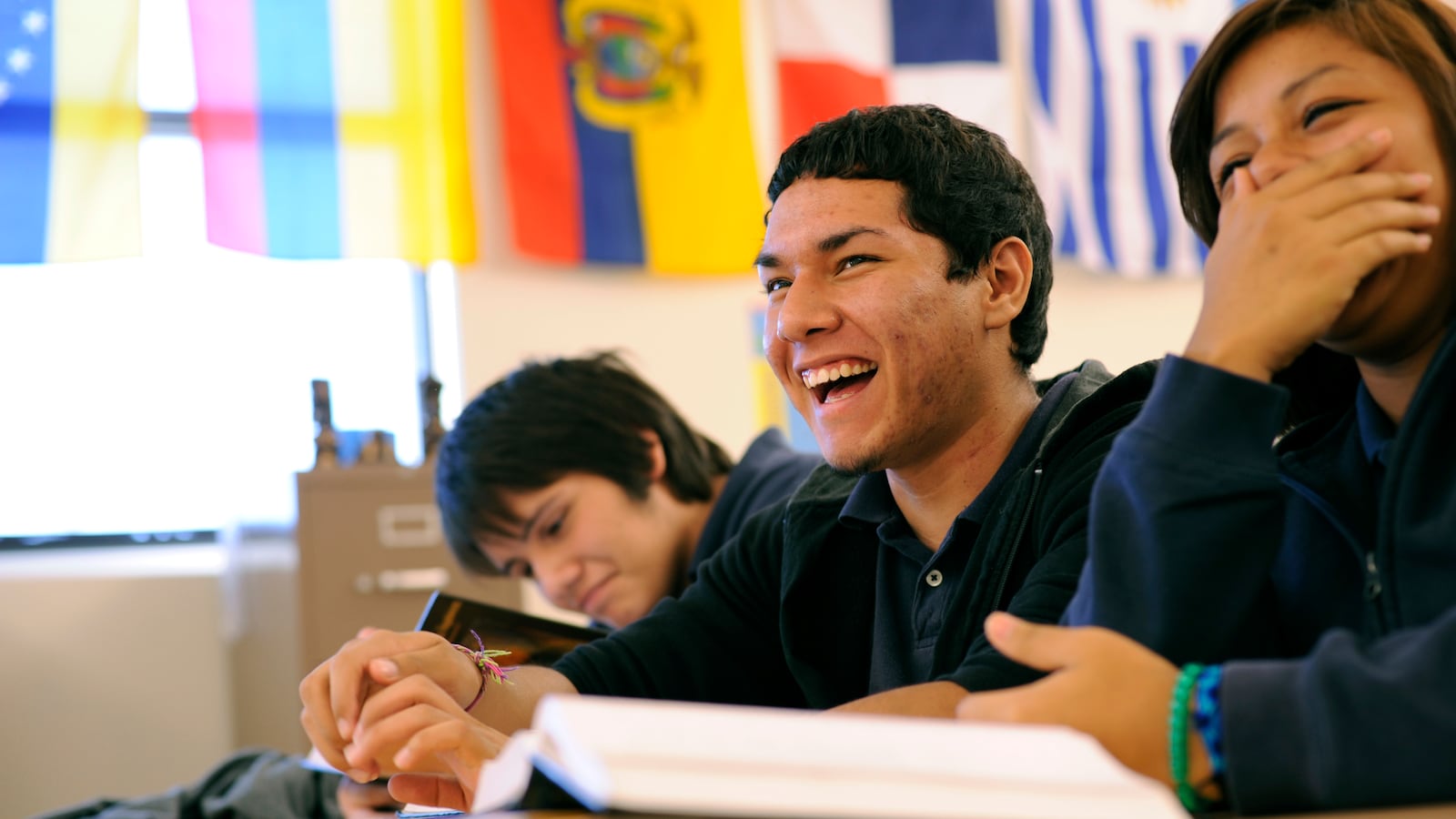 A group of high school students laughing in a classroom