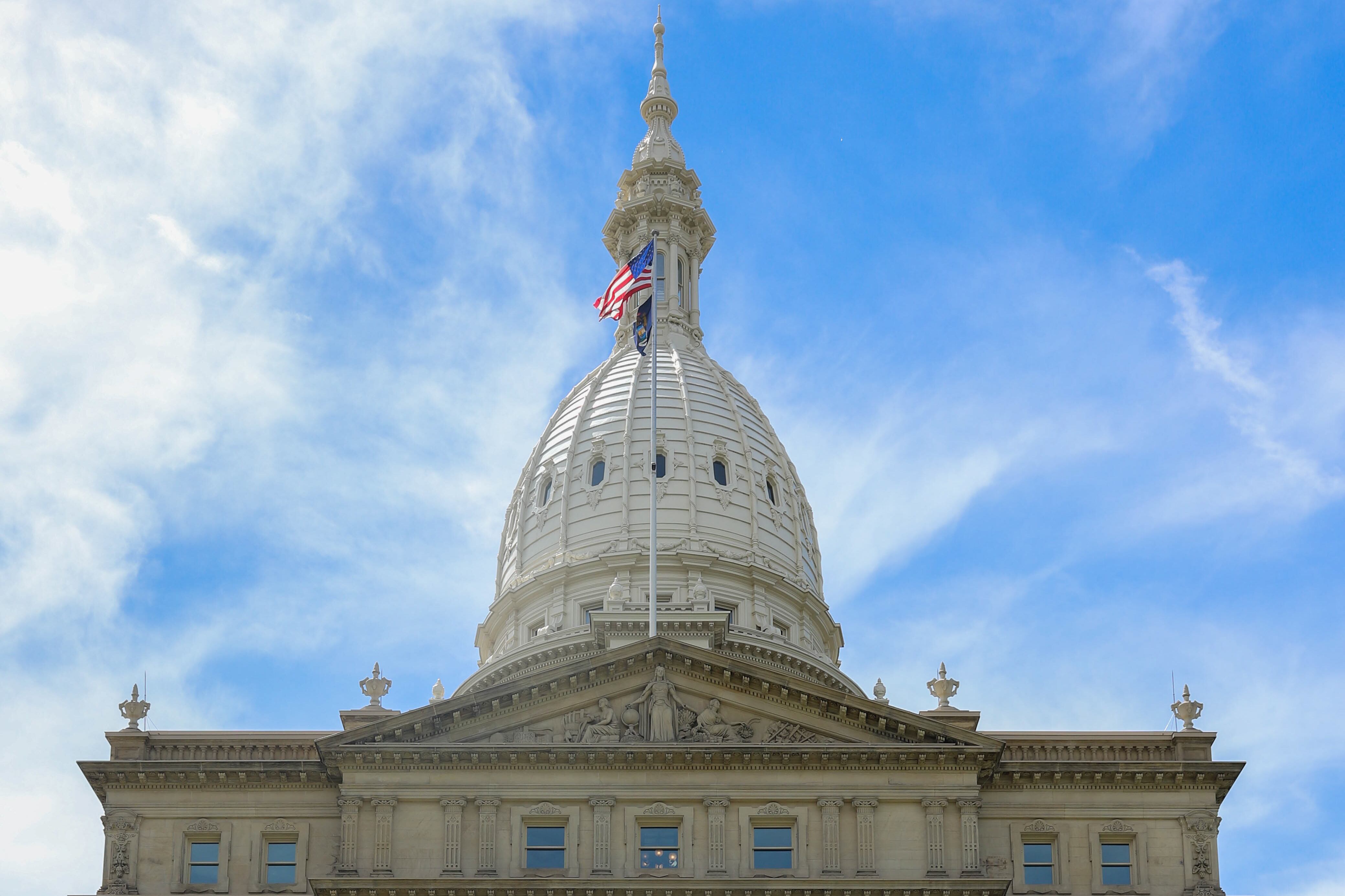 A historic building with a tall spire against a blue sky with clouds.